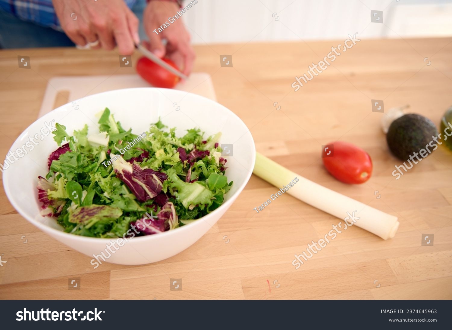 Close-up hands of a male chef chopping ripe organic tomatoes while preparing a delicious healthy salad from fresh vegetables and herbs. People. Food. Healthy eating, alimentation and dieting concept #2374645963