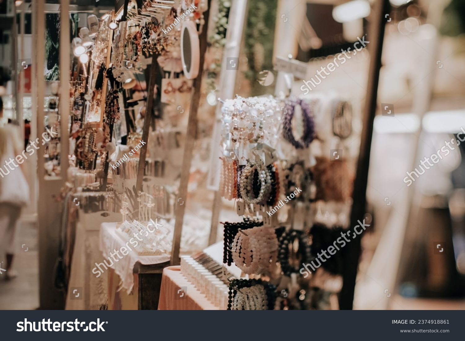 Indoor festive weekend market. Close up of hand made jewellery booth. Social pop up event in shopping mall for entrepreneurs and makers. Captured with tilt-shift lens. Selective focus; bokeh effect. #2374918861