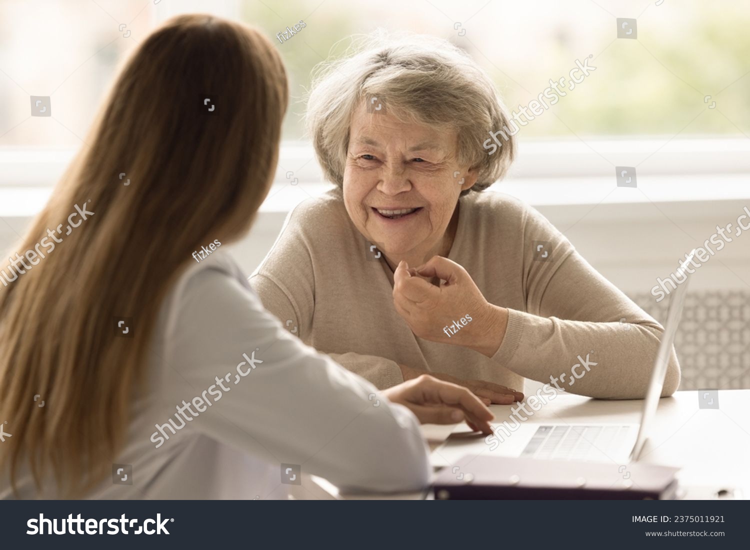 Smiling female senior patient get professional medicare in private hospital, tell about health complaint. General practitioner have consultation meeting with adult client. Eldercare, medicine, health #2375011921