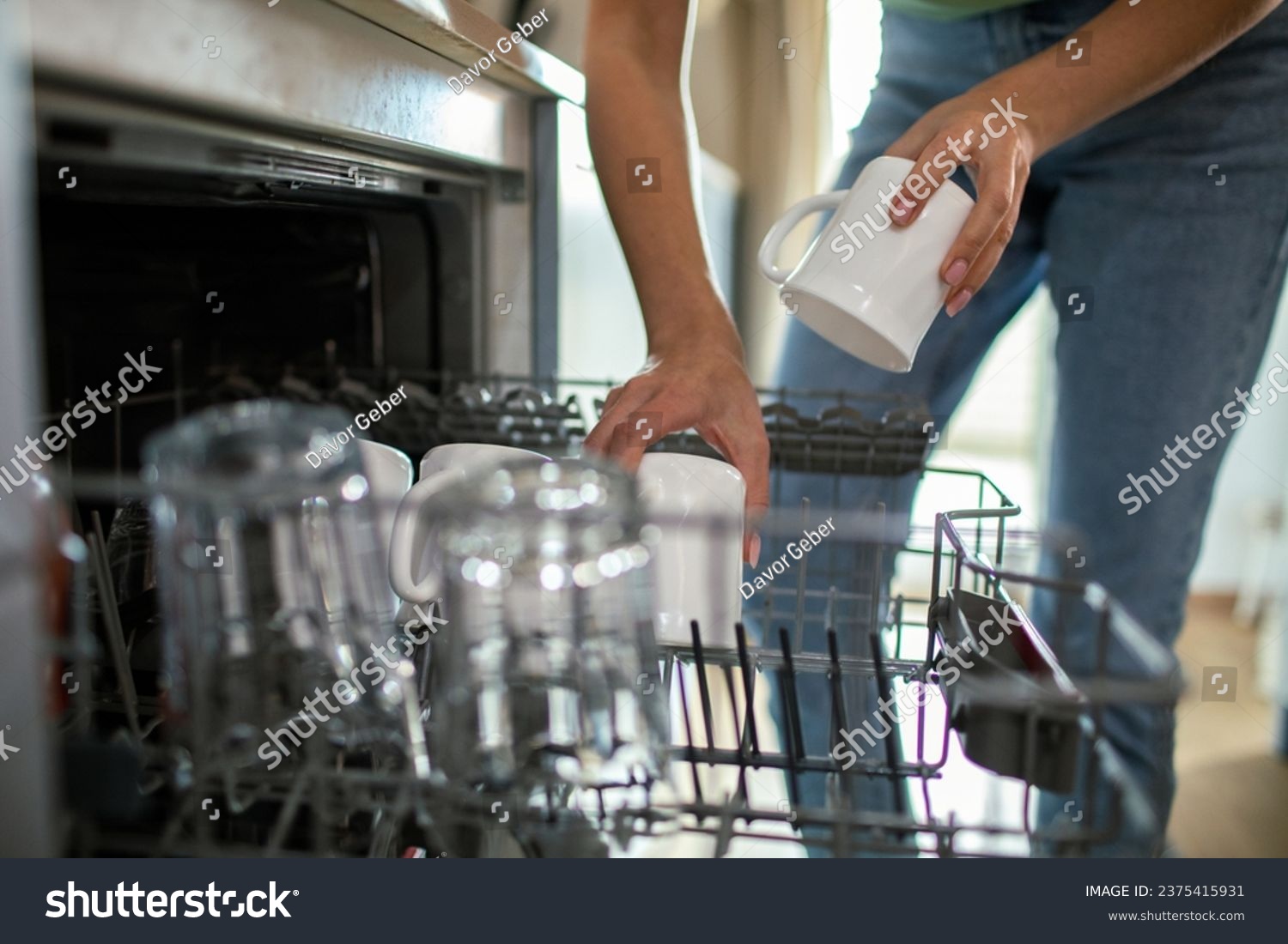 Close-Up of a young woman emptying her dish washer in the kitchen #2375415931