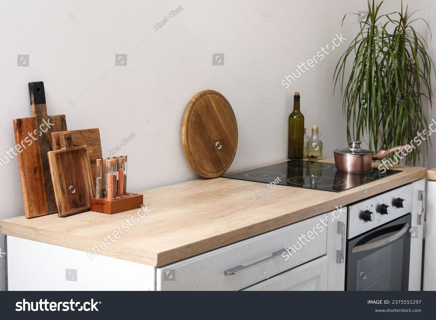 White kitchen counter with cutting boards, electric stove and condiments #2375551297