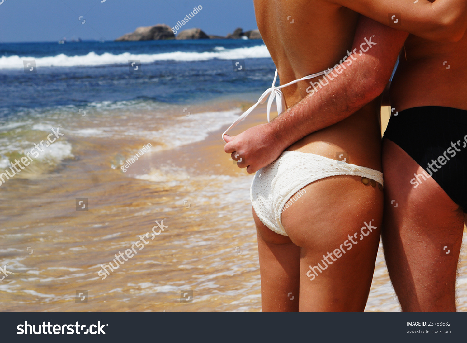 Young suntanned man and the woman in bathing suits embrace on an ocean coast #23758682
