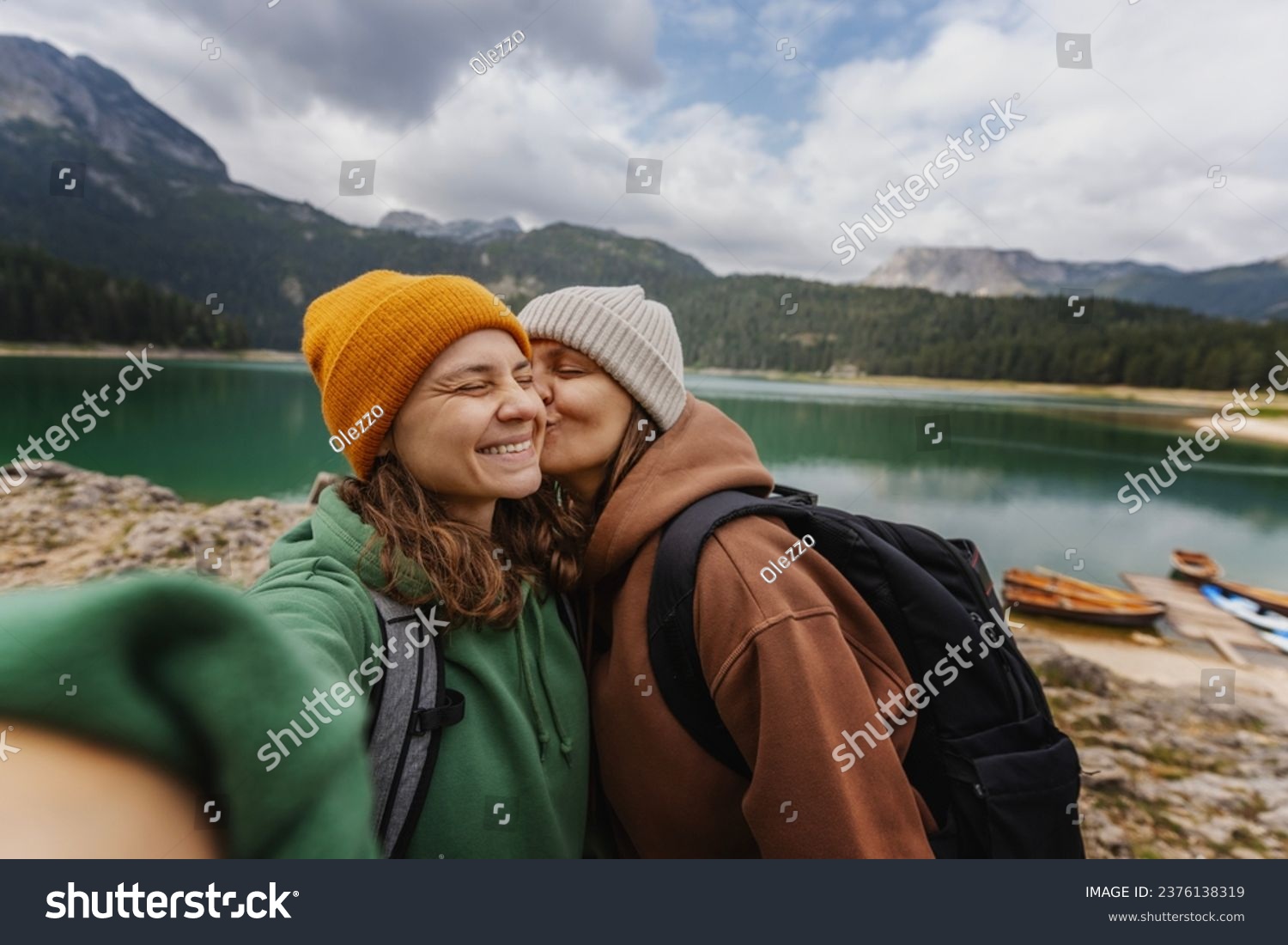 Young cheerful romantic lesbian couple traveling together in the mountains taking selfies  #2376138319