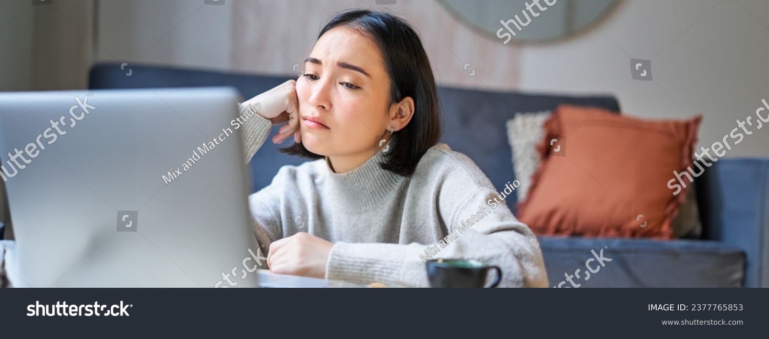 Portrait of korean girl sits bored, student looks gloomy at laptop, sitting at home and expressing boredom. #2377765853