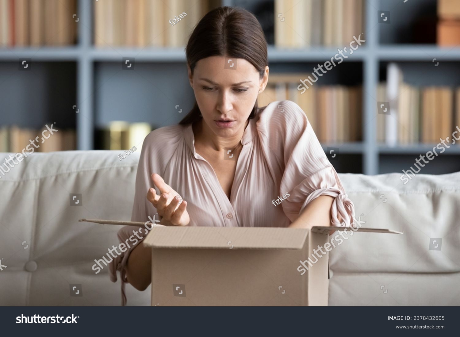 Woman sitting on couch put on lap carton box opened it feels disillusioned parcel arrives damaged broken or mixed up goods, negative feedback, wrong order, bad product quality, return refund concept #2378432605