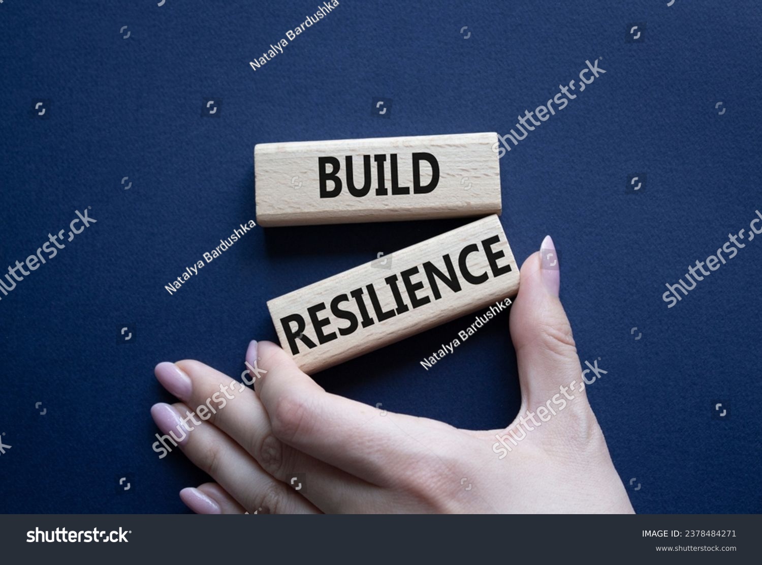Build resilience symbol. Wooden blocks with words Build resilience. Beautiful deep blue background. Businessman hand. Business and Build resilience concept. Copy space. #2378484271