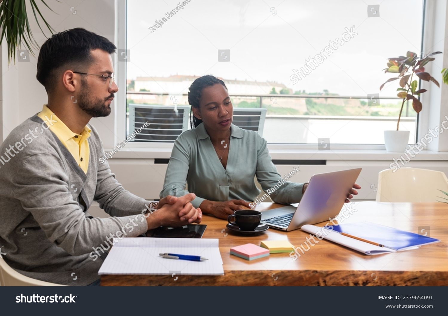Two young freelance business people, staff meeting, analysing and advisory at modern office. Business partners, small company owners, working on new project. Brainstorming concept #2379654091