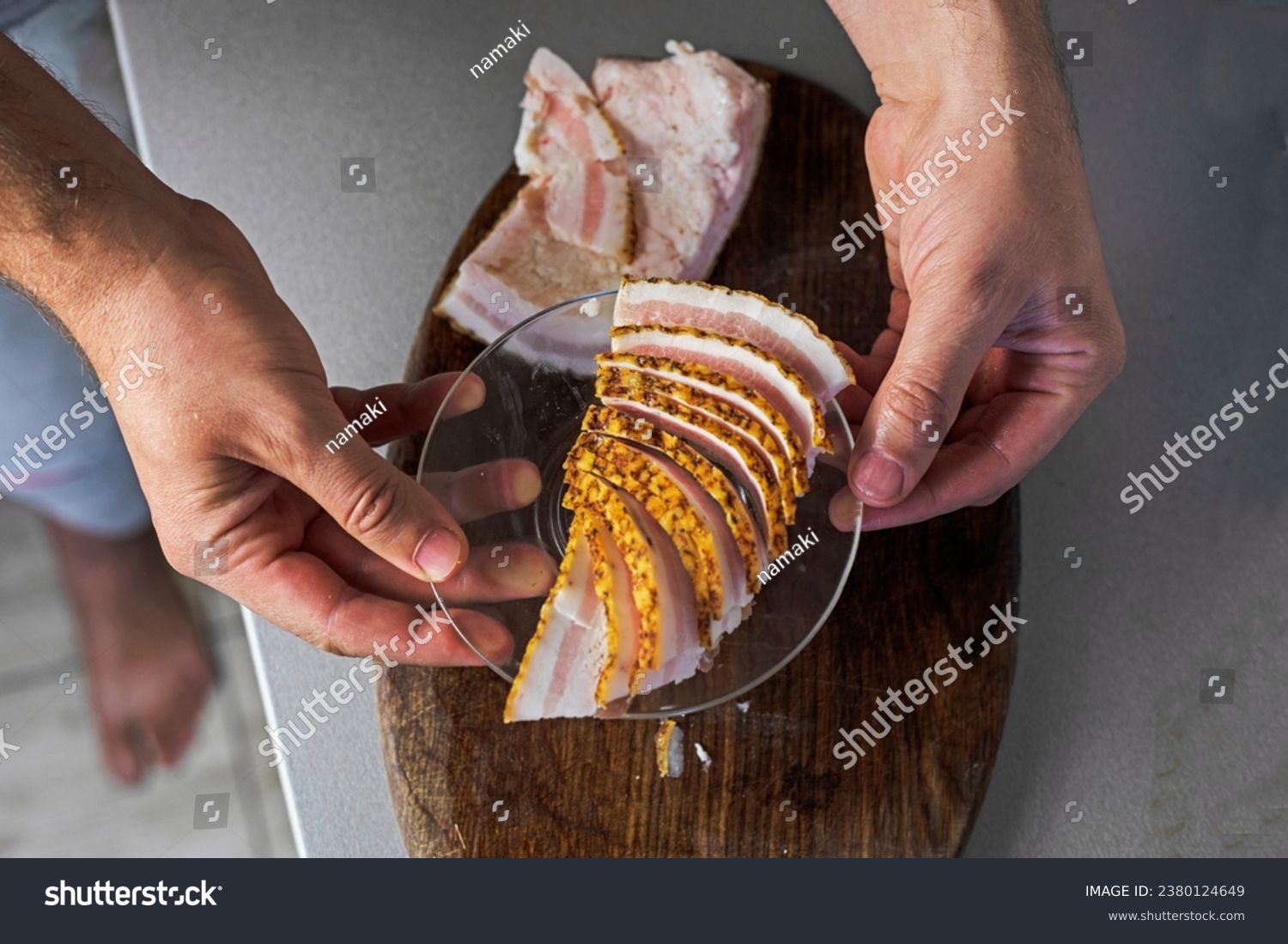Use your hand to pick up thin pieces of chopped bacon on a cutting board and place on a plate. flatlay #2380124649