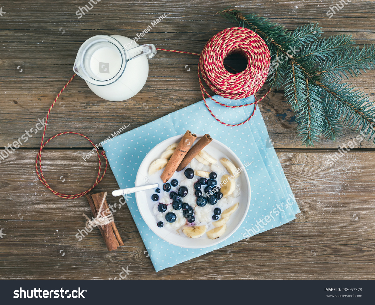 Rice porridge with milk, cinnamon, banana and blueberry with Christmas (New Year) decorations on a rustic wood background. Top view #238057378