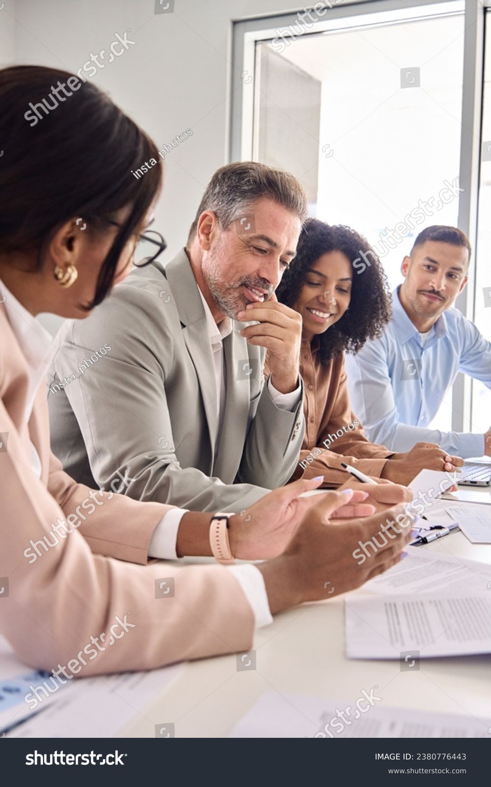 Busy diverse professional business team having discussion at office meeting. Financial advisors or managers consulting senior business man investor talking sitting at conference table. Vertical shot. #2380776443