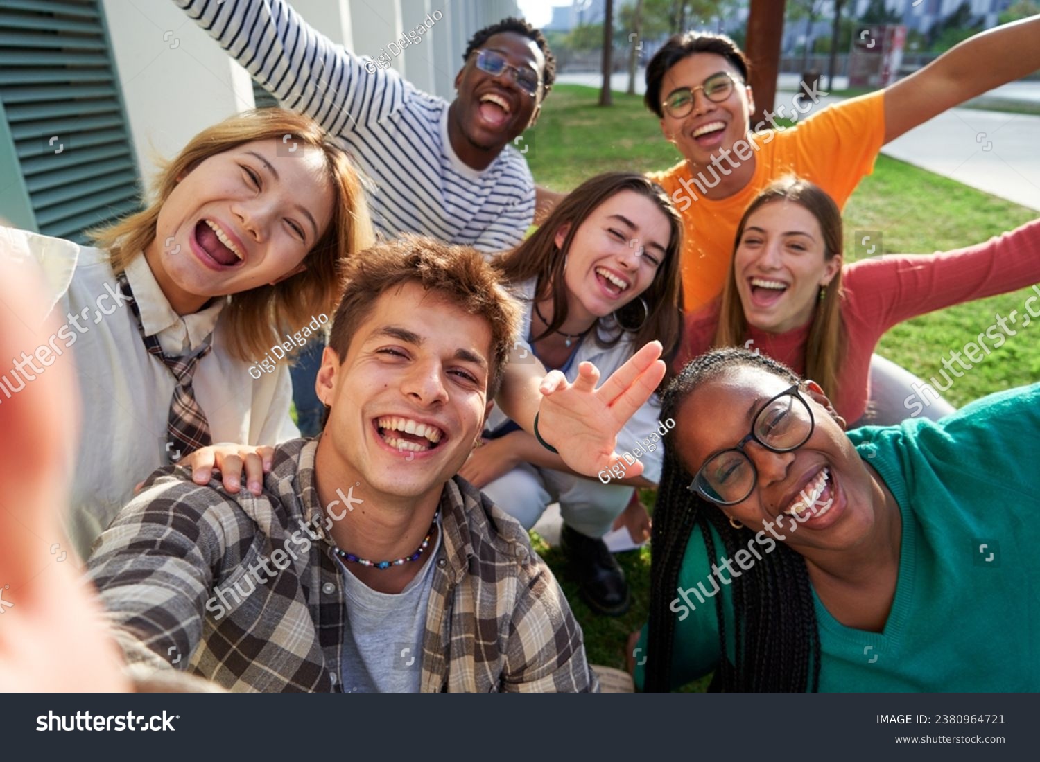 Happy group of multiethnic classmate taking a selfie outdoors in the university campus, looking at camera cheerfully raising arms, celebrating last day. #2380964721