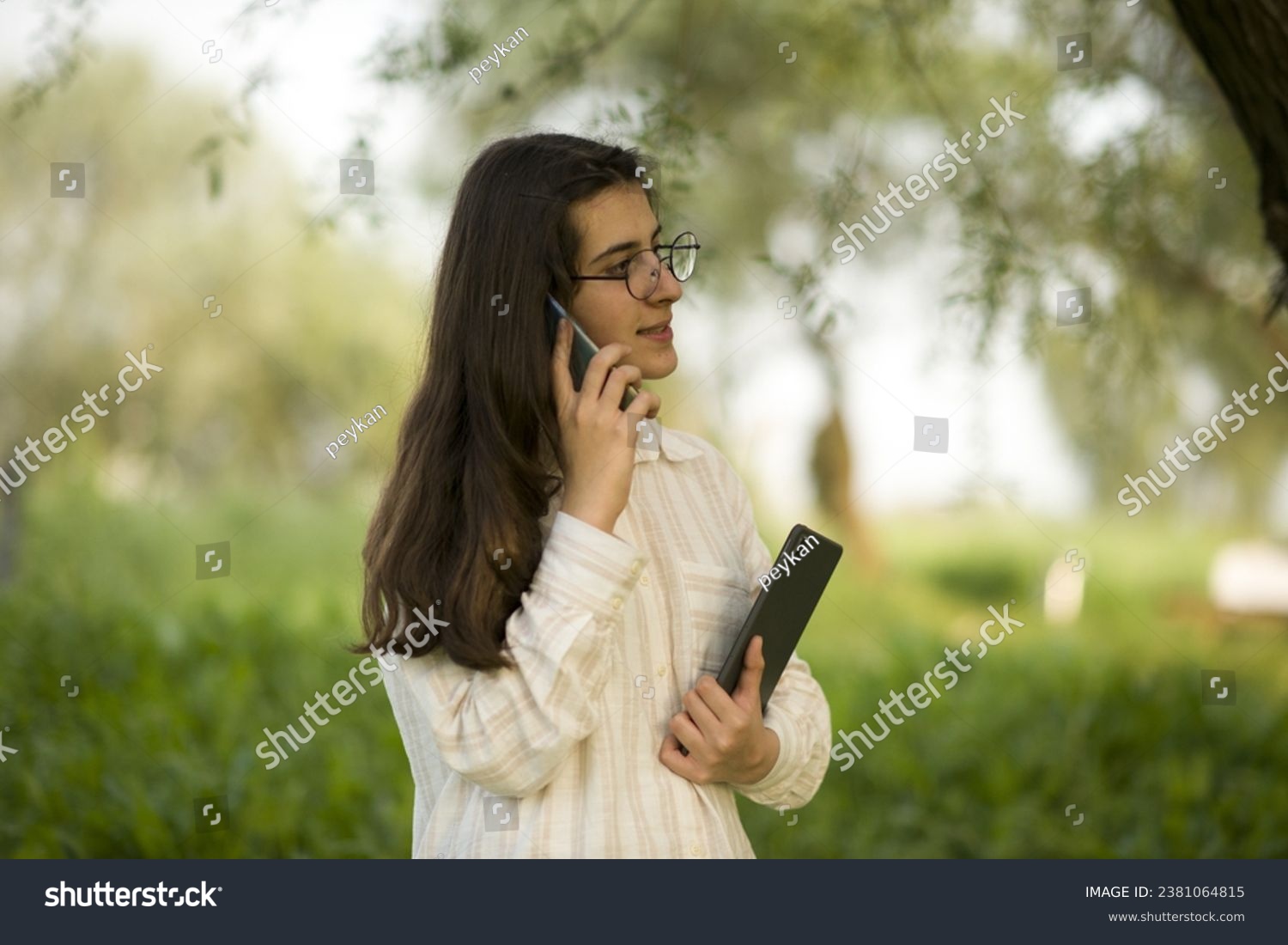 Young business woman having a job interview on the phone, doing business analysis, in the garden of the office, by the lake #2381064815