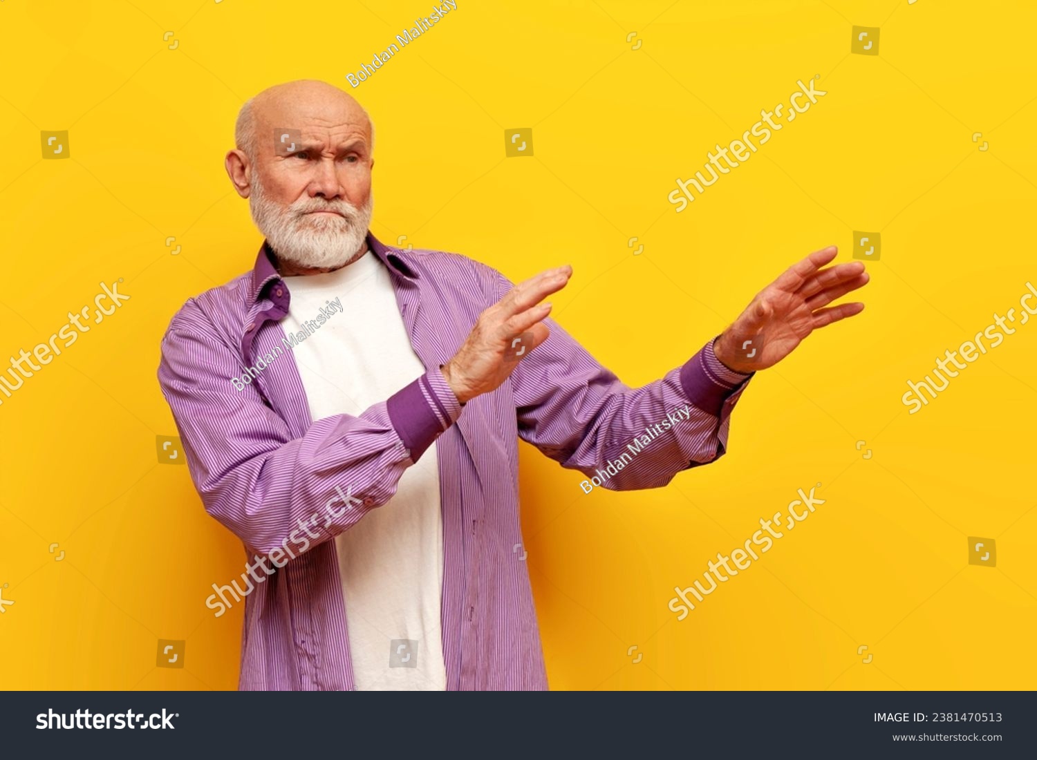 dissatisfied old bald grandfather with gray beard avoids and ignores on yellow isolated background, elderly pensioner rejects and refuses with hands #2381470513