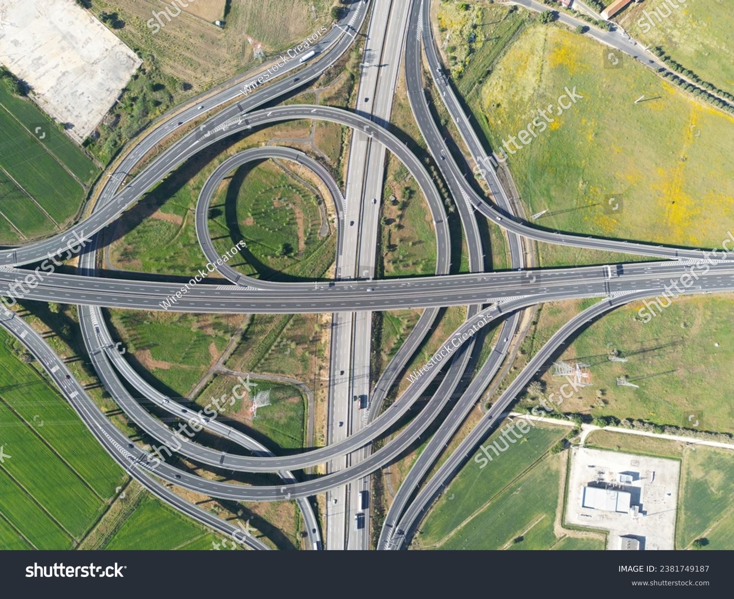 Aerial view of a four-lane highway intersection with a car driving along one of the lanes #2381749187