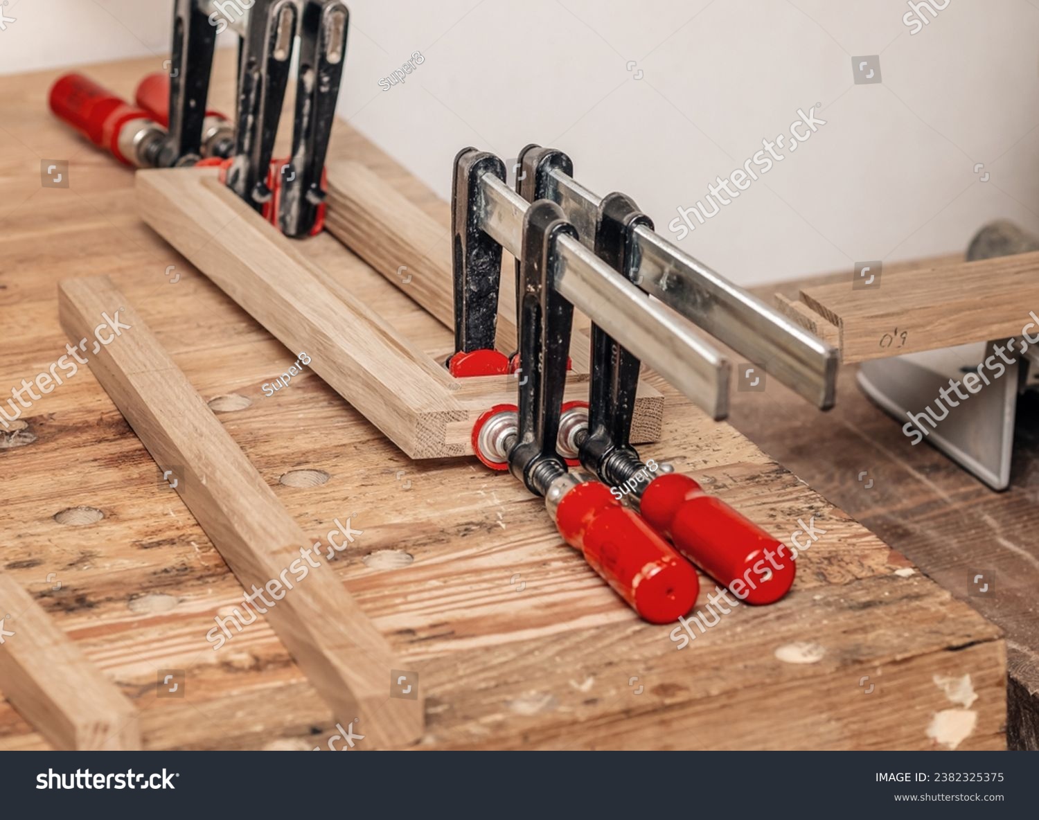 Carpenter clamps are fixed to boards. Gluing joinery in the workshop #2382325375