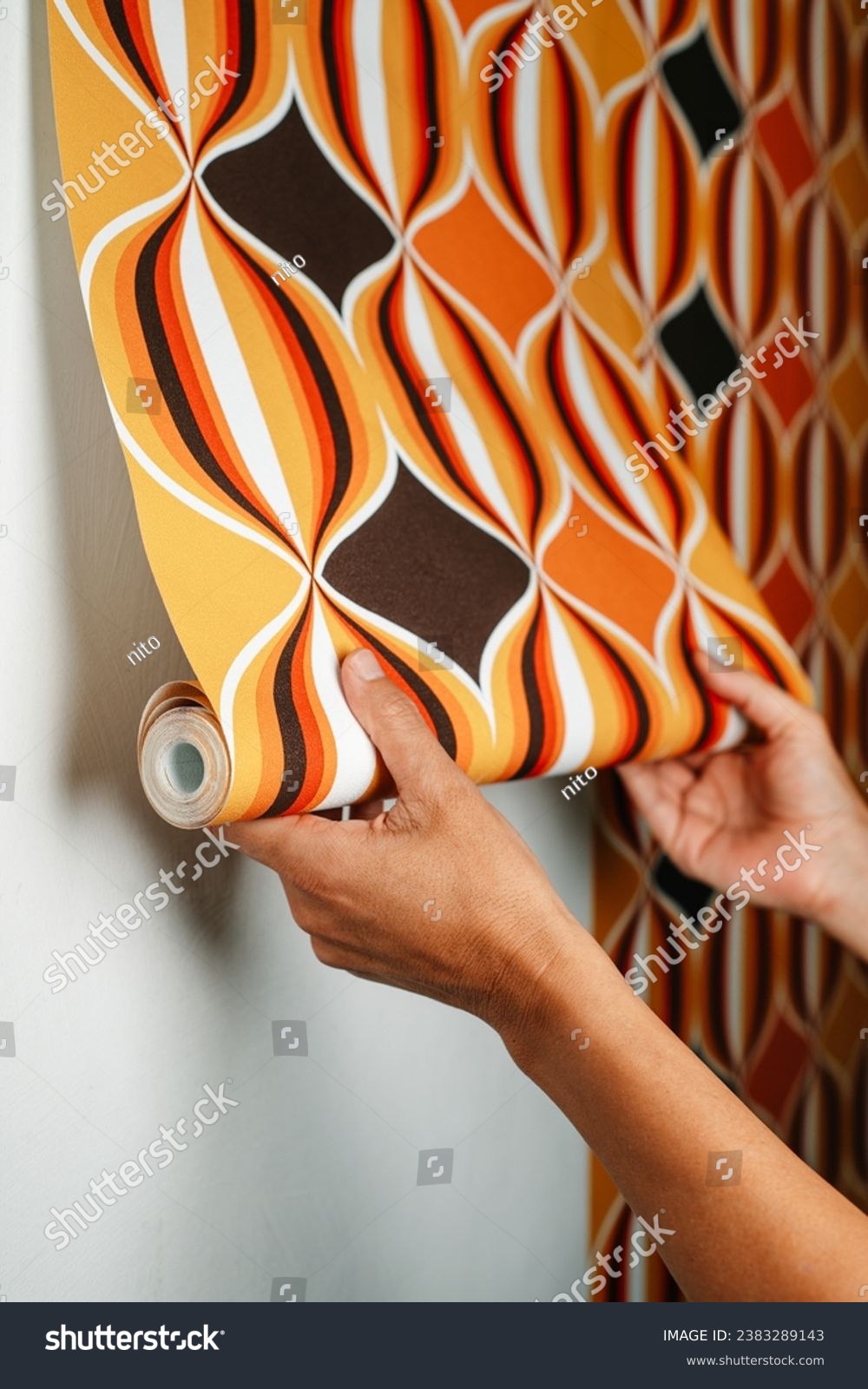 a caucasian man attaches a geometric patterned wallpaper to a white wall #2383289143