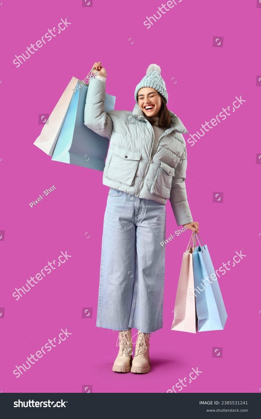 Young woman in winter clothes with shopping bags on purple background #2385531241