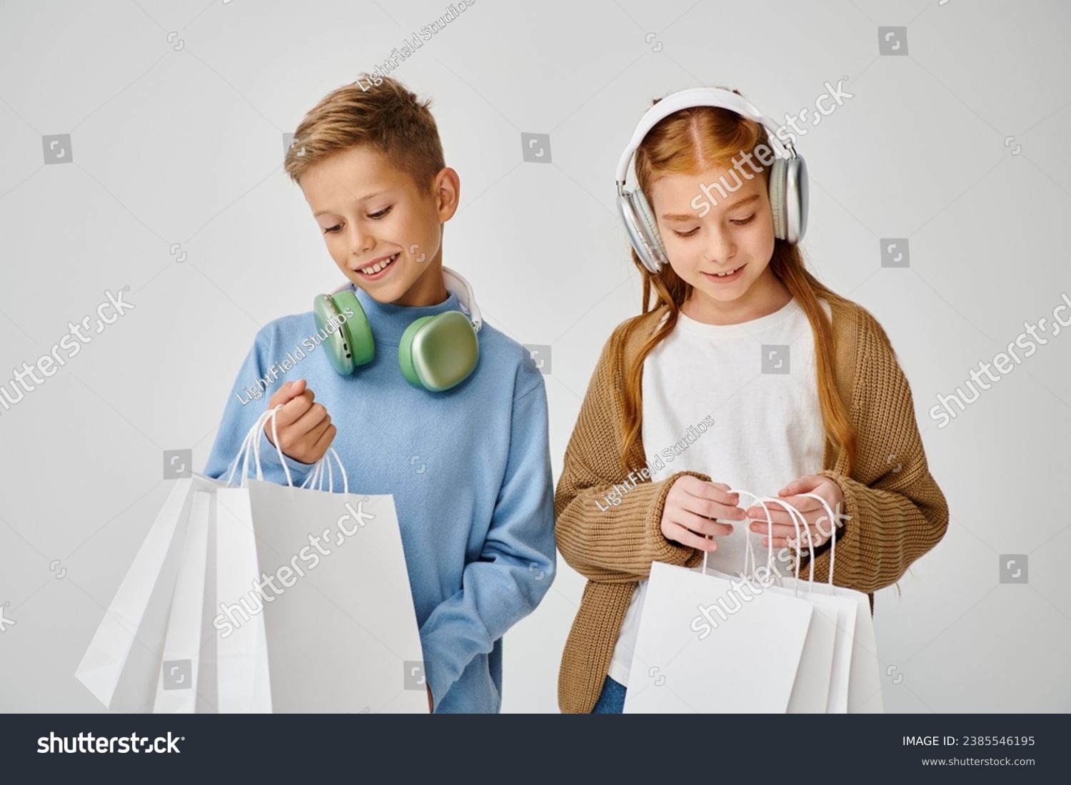jolly little friends with headphones looking in their present bags, Black Friday, fashion concept #2385546195