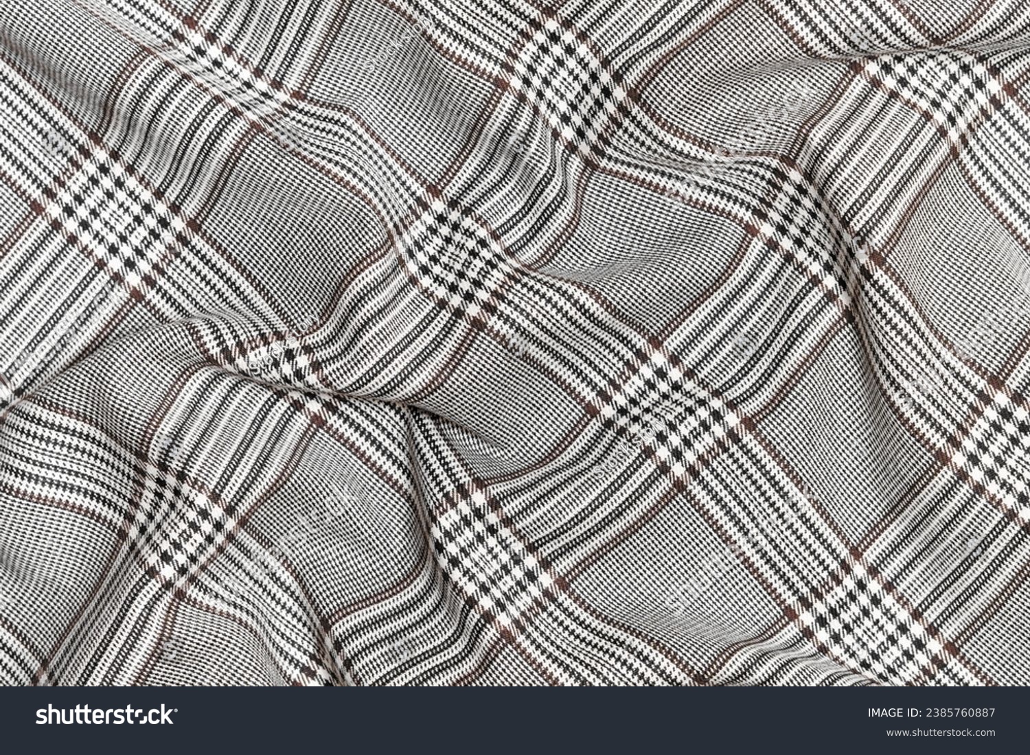 Crumpled, wrinkled fabric of black and brown colors in tartan check close-up. Traditional Scottish clothing. place for your design #2385760887