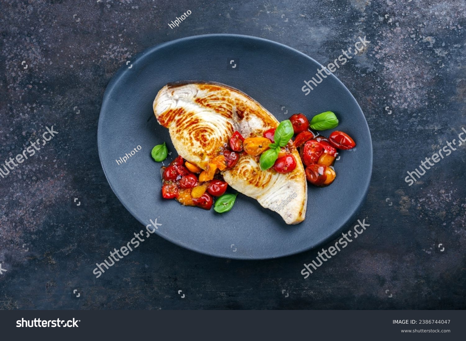 Roasted swordfish steak with tomatoes and paprika served as top view on a design plate #2386744047