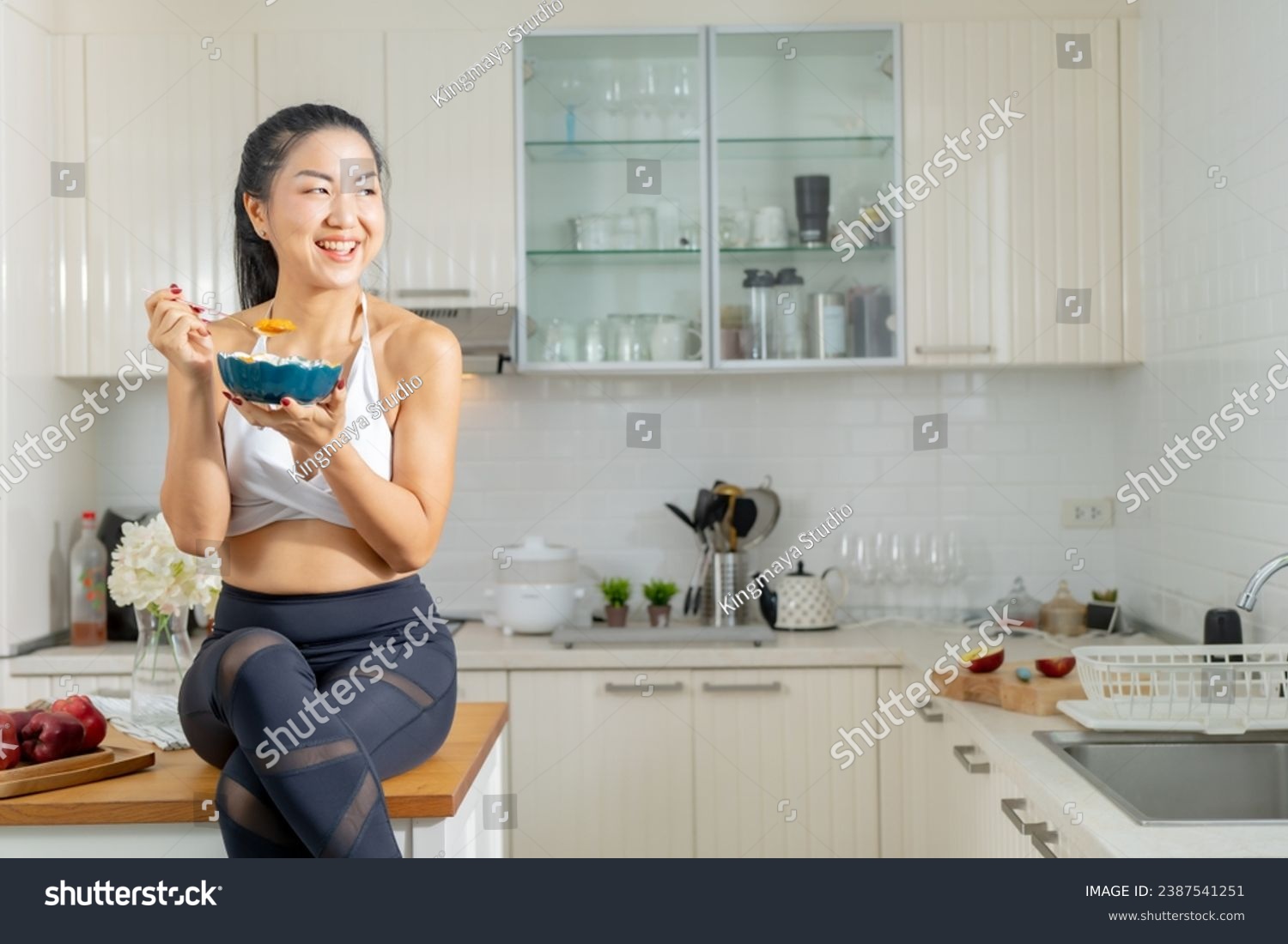 A healthy Asian woman in exercise clothes Is happily cooking a healthy meal in her home kitchen in the morning. Healthy care concept, Healthy fruits every day. #2387541251
