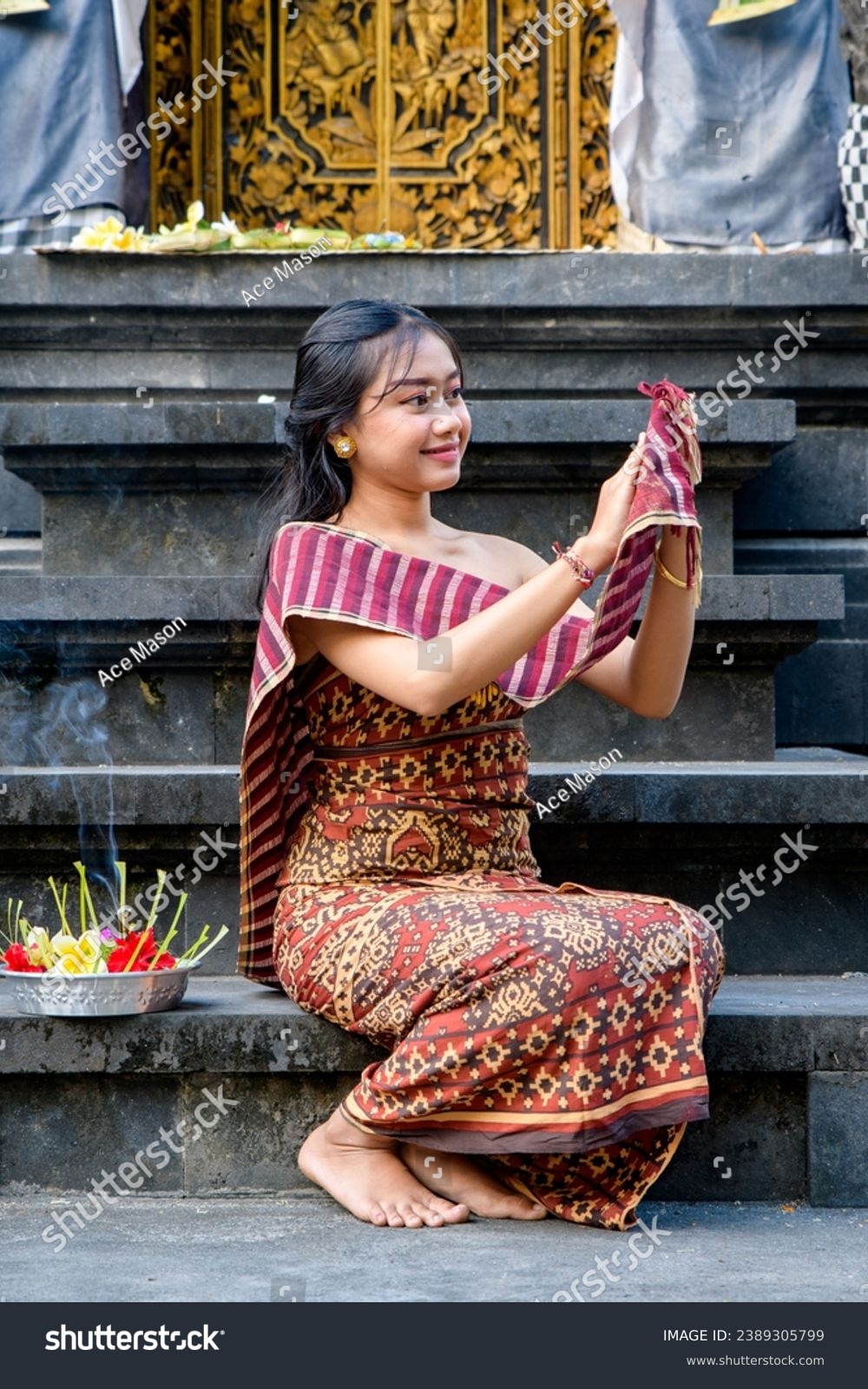 Woman in traditional clothing making an offering at a temple #2389305799