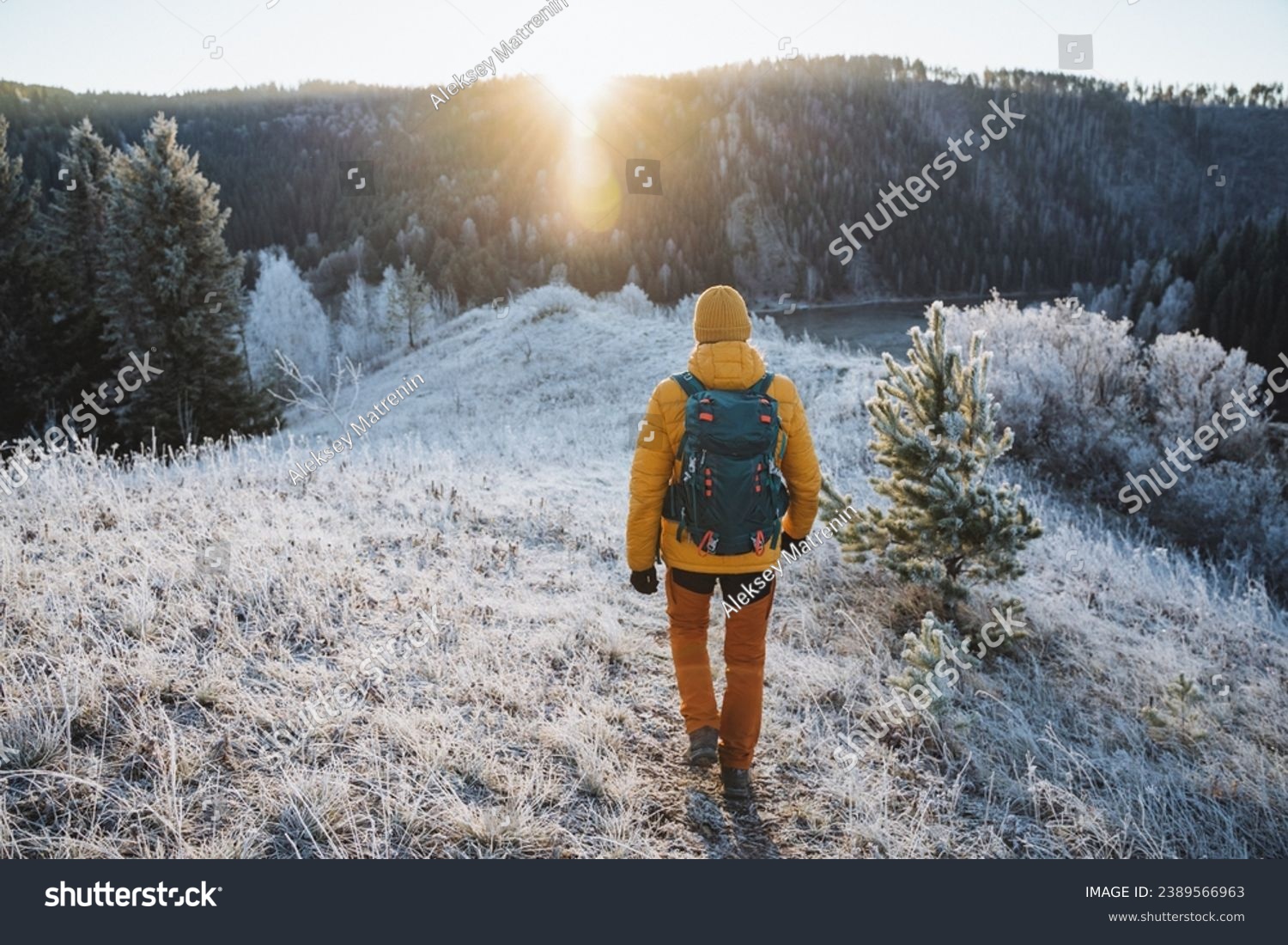 Rear view of man with backpack on hiking trip, solo trekking in the mountains, hiking with backpack in nature in winter season. High quality photo #2389566963