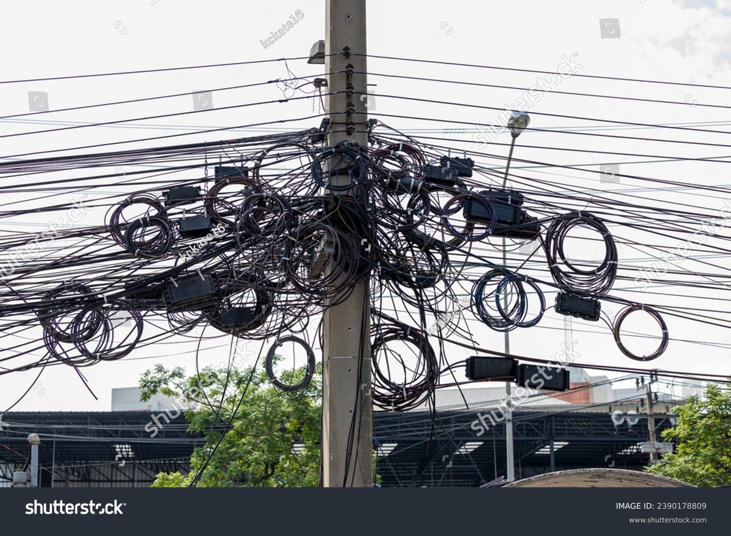 Intertwined electric wires. A tangled electrical wires showcasing the complexities of the city's power supply system. telephone wires and wireless provider cables. #2390178809