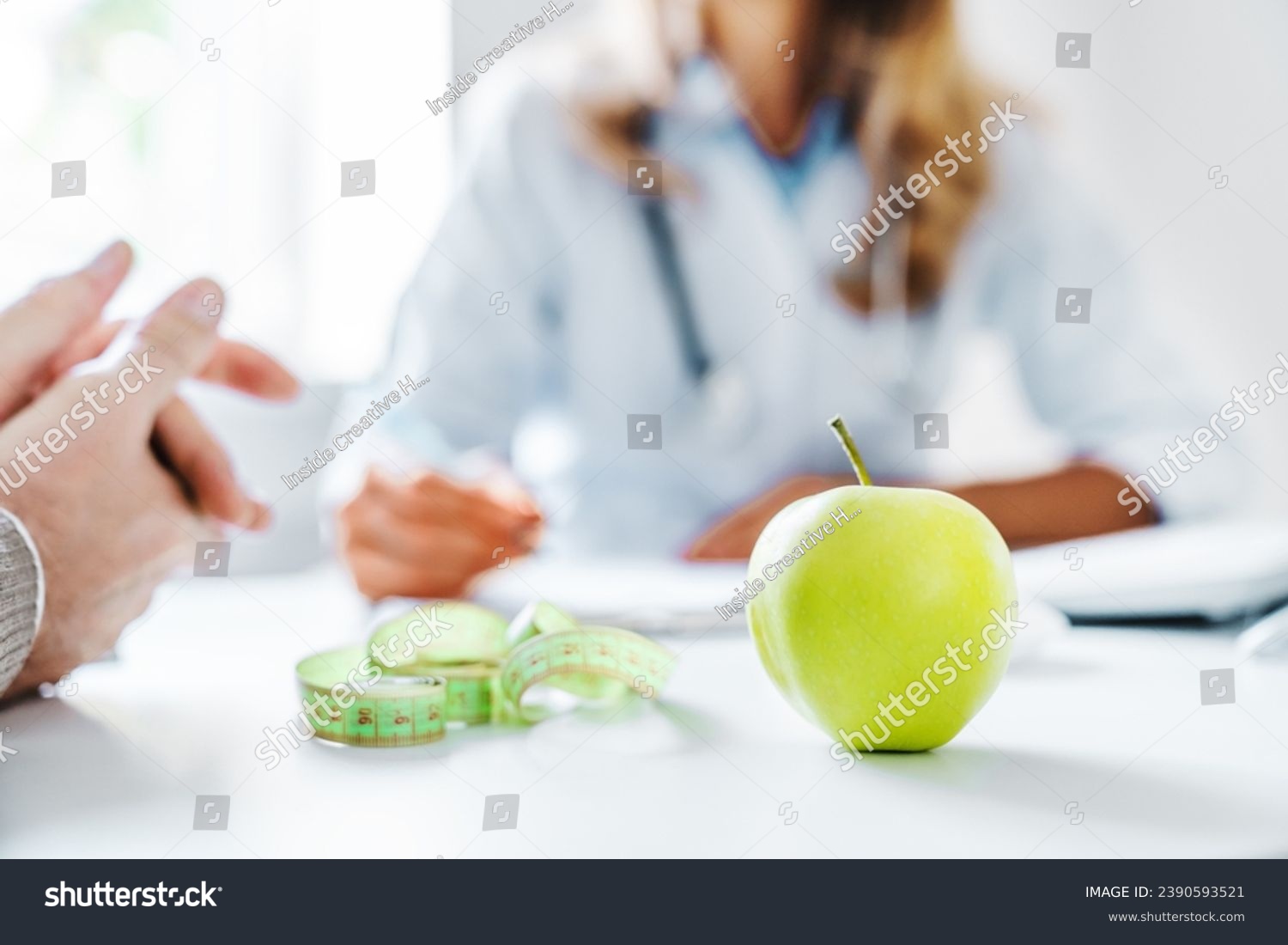 Healthy food concept. Cropped close up of woman doctor dietician recommending senior male patient fresh apple. Weight loss, diet for burning calories. Eating disorder issues #2390593521