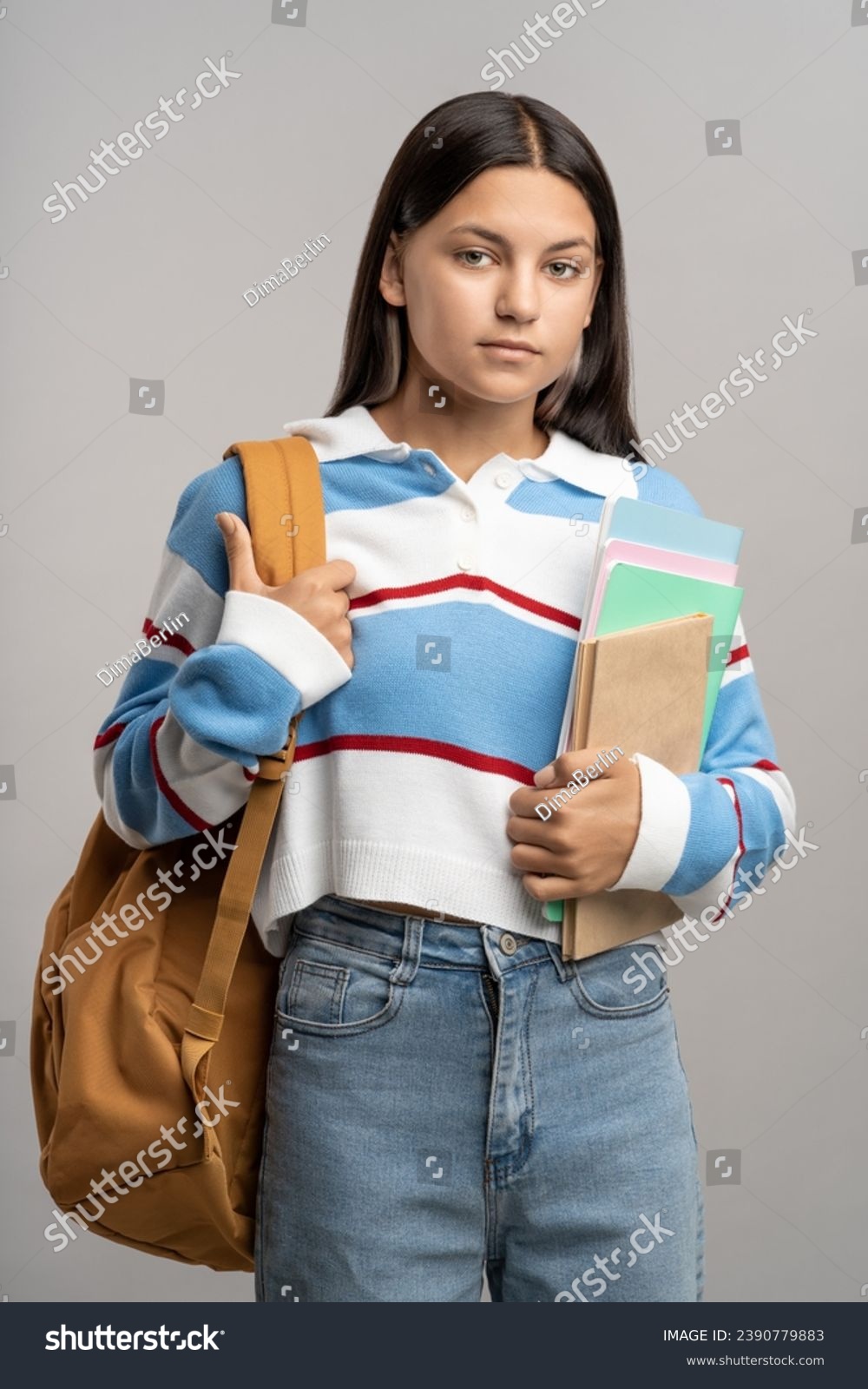 Teenage girl with backpack and notebooks. Serious unsmiling girl in confident pose looking at camera. Ready for hard studying in university college, teenager isolated on gray, studio portrait. #2390779883