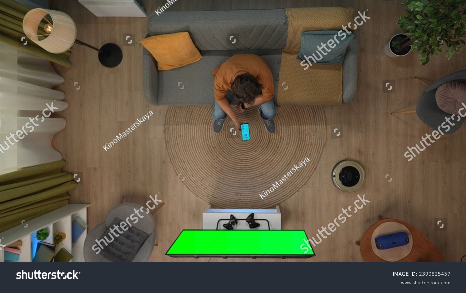Top view of man sitting on the sofa holding smartphone looking at app for gadgets, tv with chroma key green screen. #2390825457