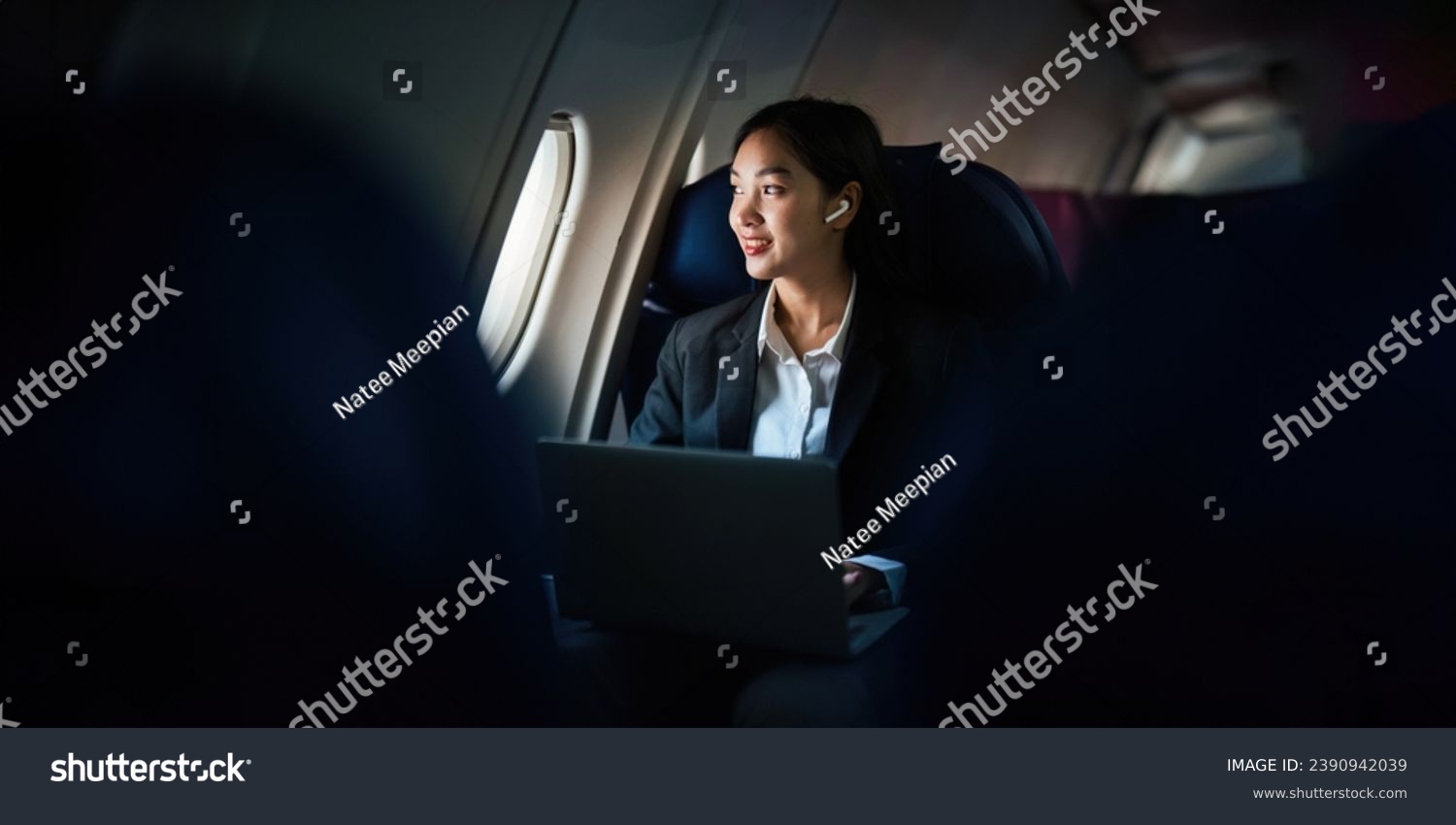 Successful Asian business woman, Business woman working in airplane cabin during flight on laptop computer listening to music with headphones #2390942039