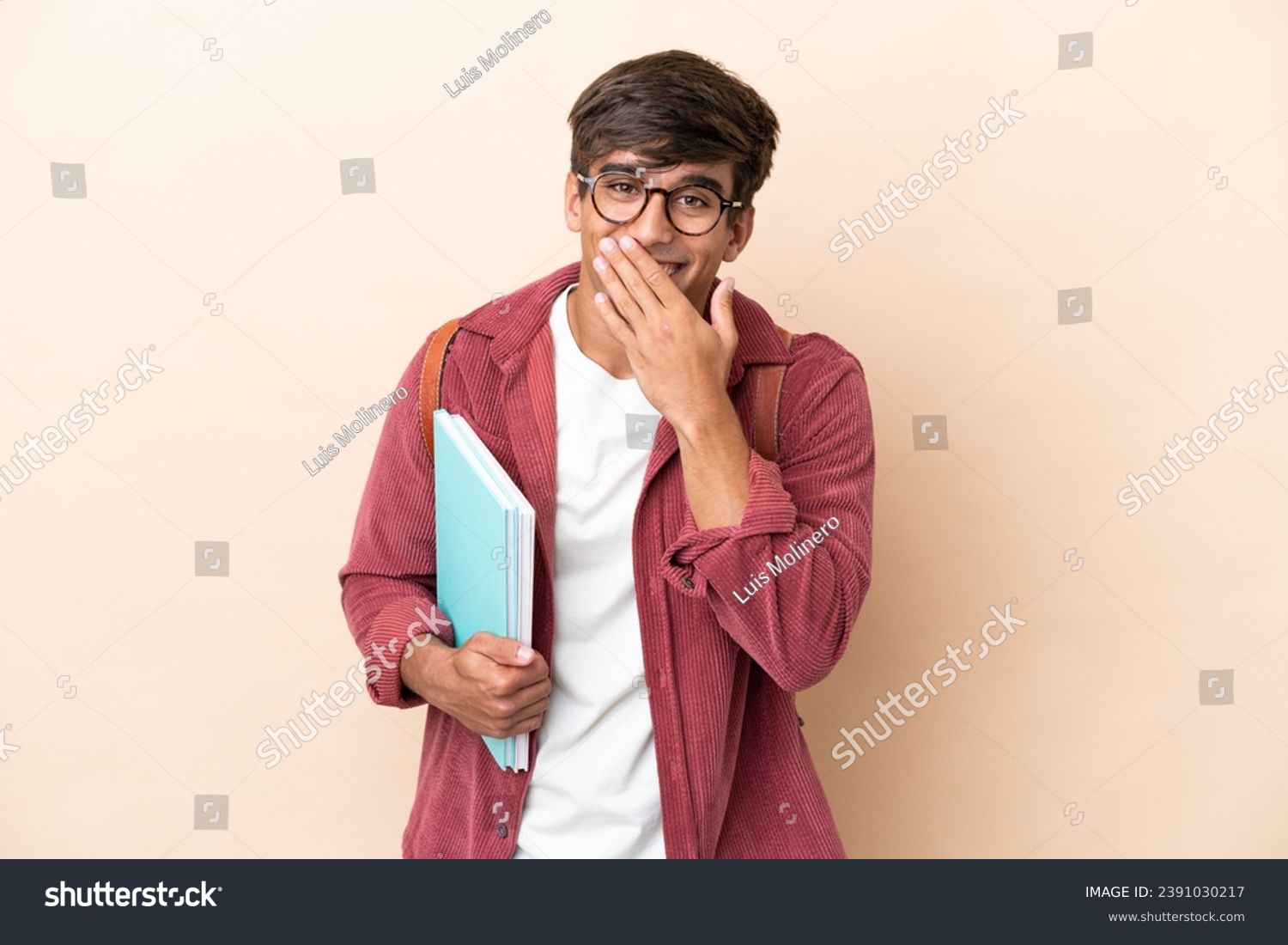 Young student caucasian man isolated on ocher background happy and smiling covering mouth with hand #2391030217