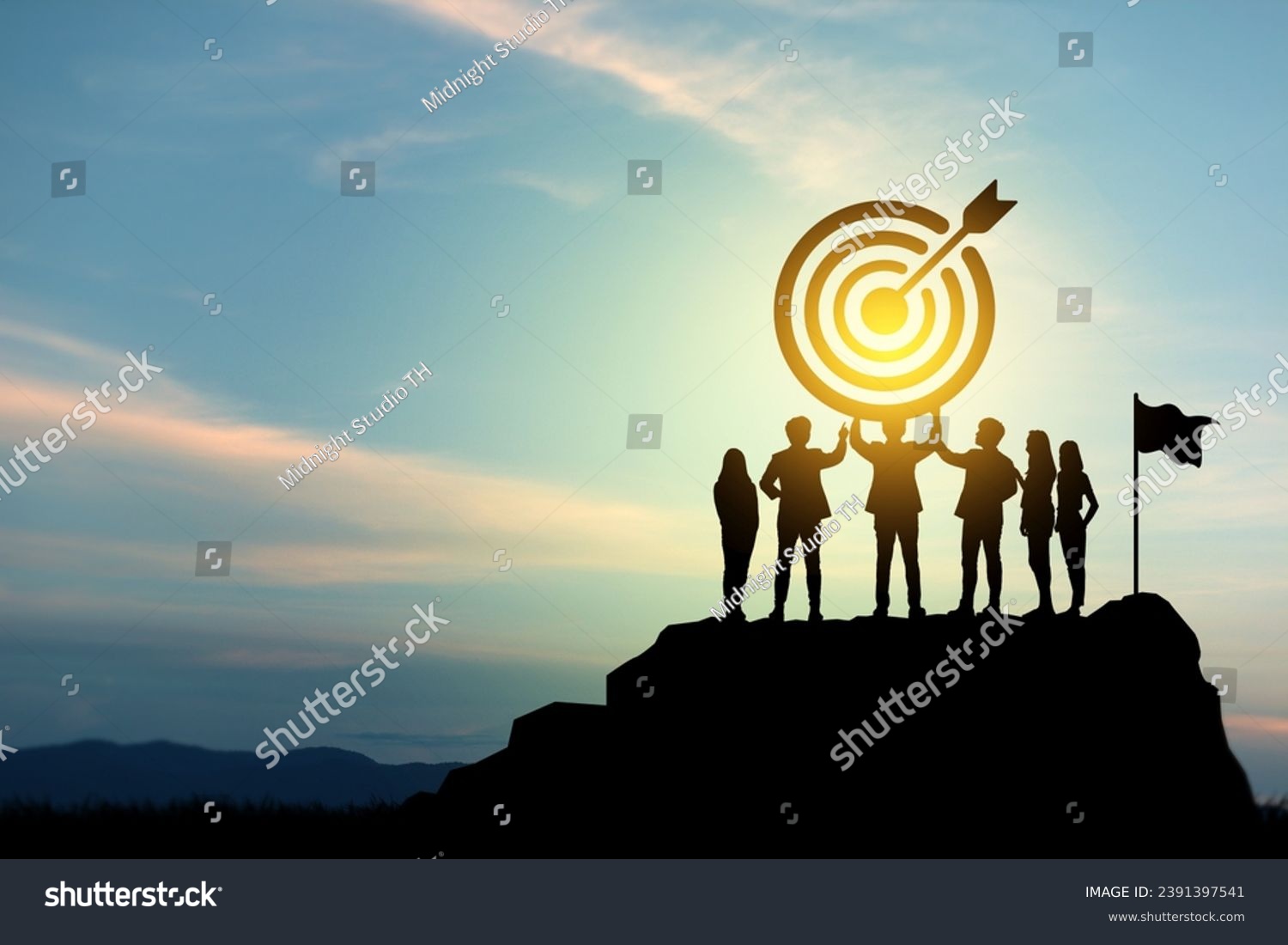 Goal setting towards planning for the future. Silhouettes of group businessmen holding target boards with flags planted on a mountain. Concept of a clear planning process and teamwork. #2391397541