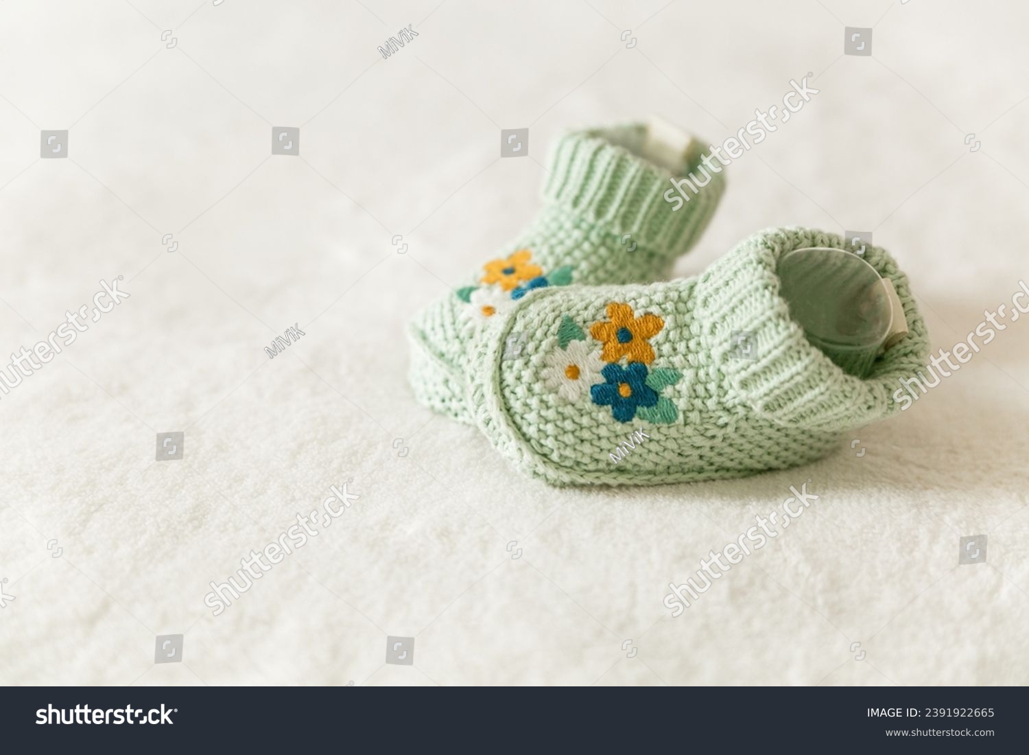 Beautiful knitted baby socks with embroidery, handmade knitted booties on a white background with copy space. Pregnancy and motherhood concept, first birthday, handmade socks, baby warm clothes #2391922665