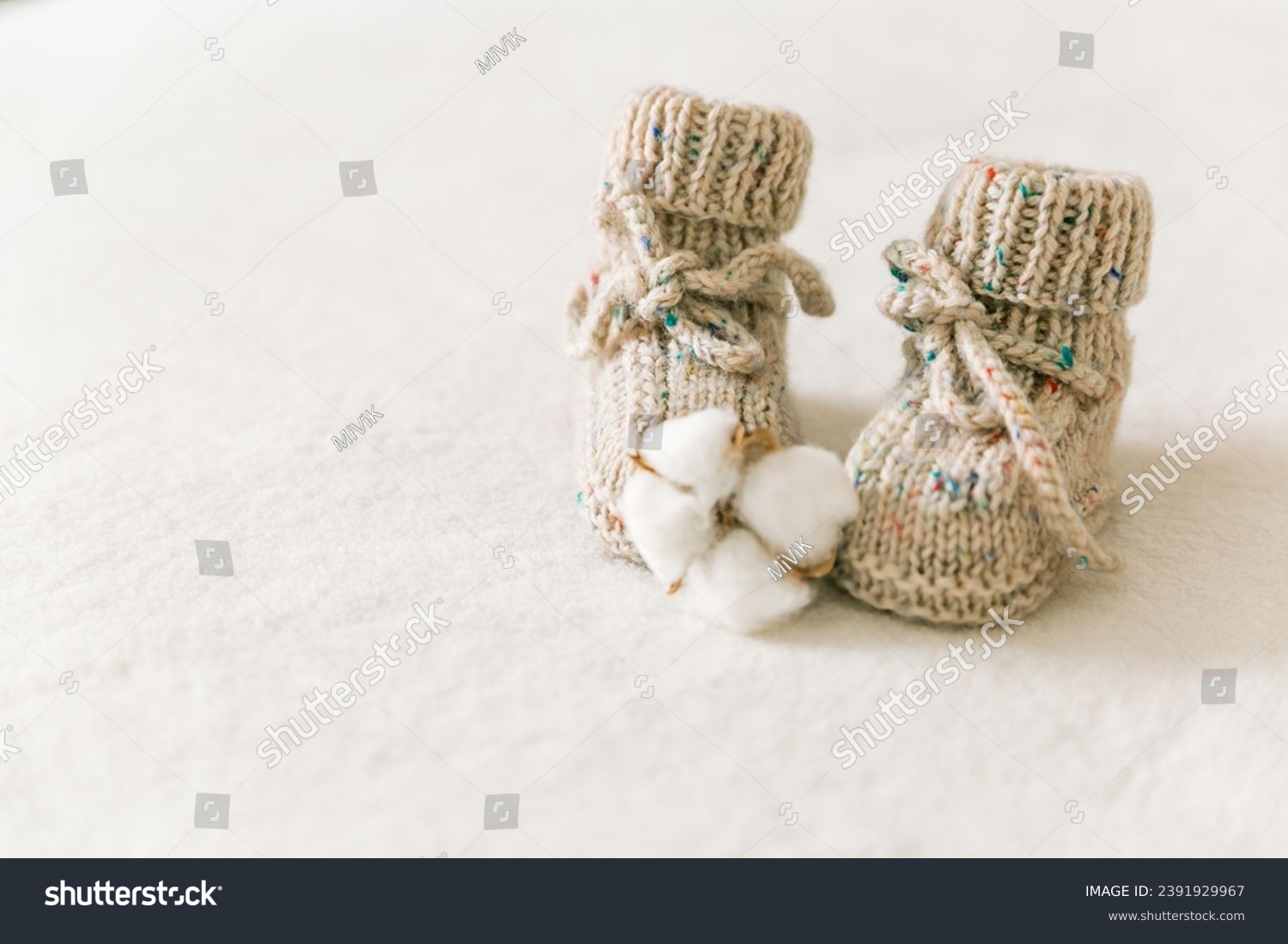 Knitted baby socks, booties on a white background with copy space. Pregnancy and motherhood concept, first birthday banner, handmade socks, baby warm clothes, handmade knitted socks, hobby. #2391929967