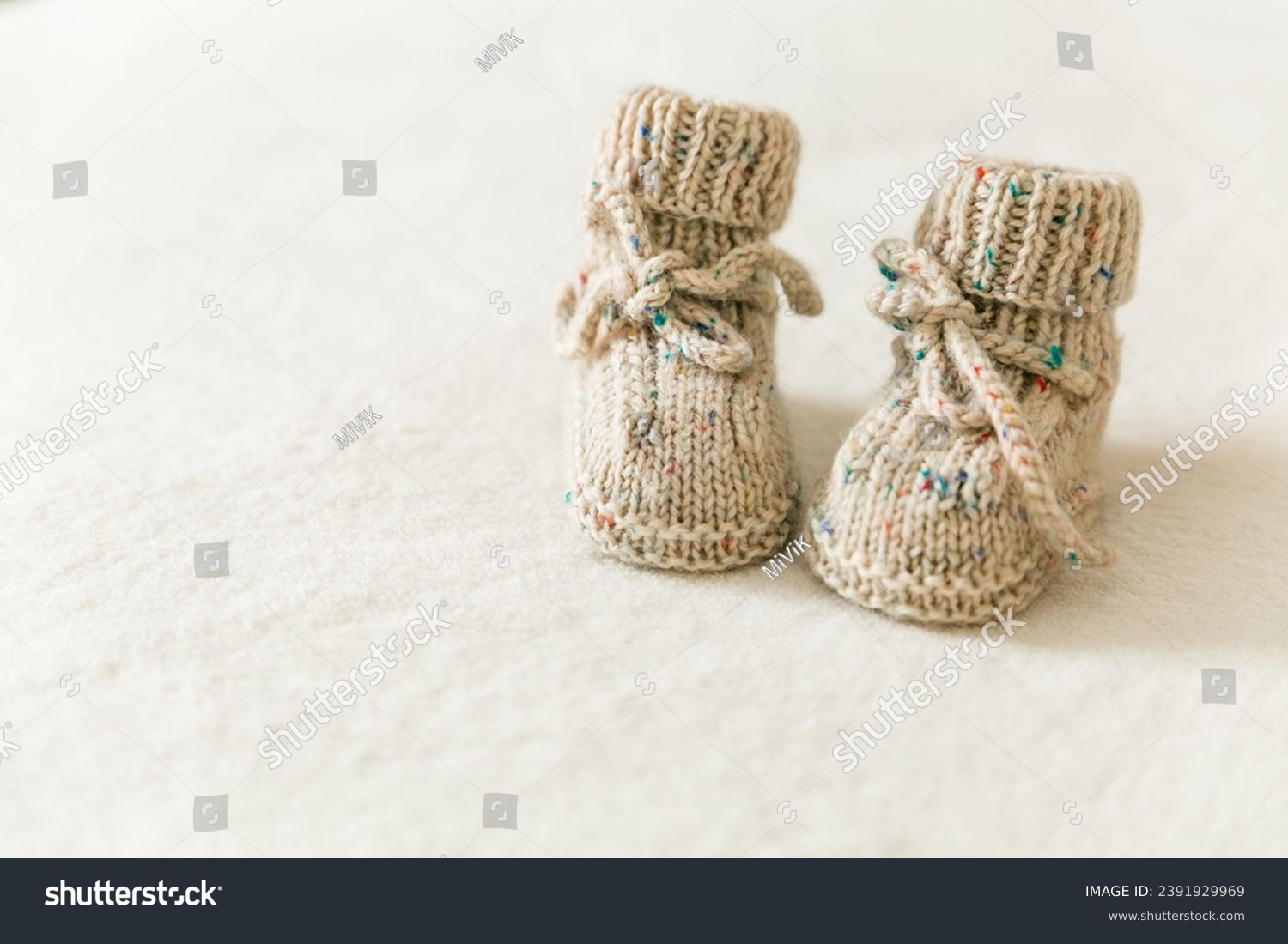 Knitted baby socks, booties on a white background with copy space. Pregnancy and motherhood concept, first birthday banner, handmade socks, baby warm clothes, handmade knitted socks, hobby. #2391929969