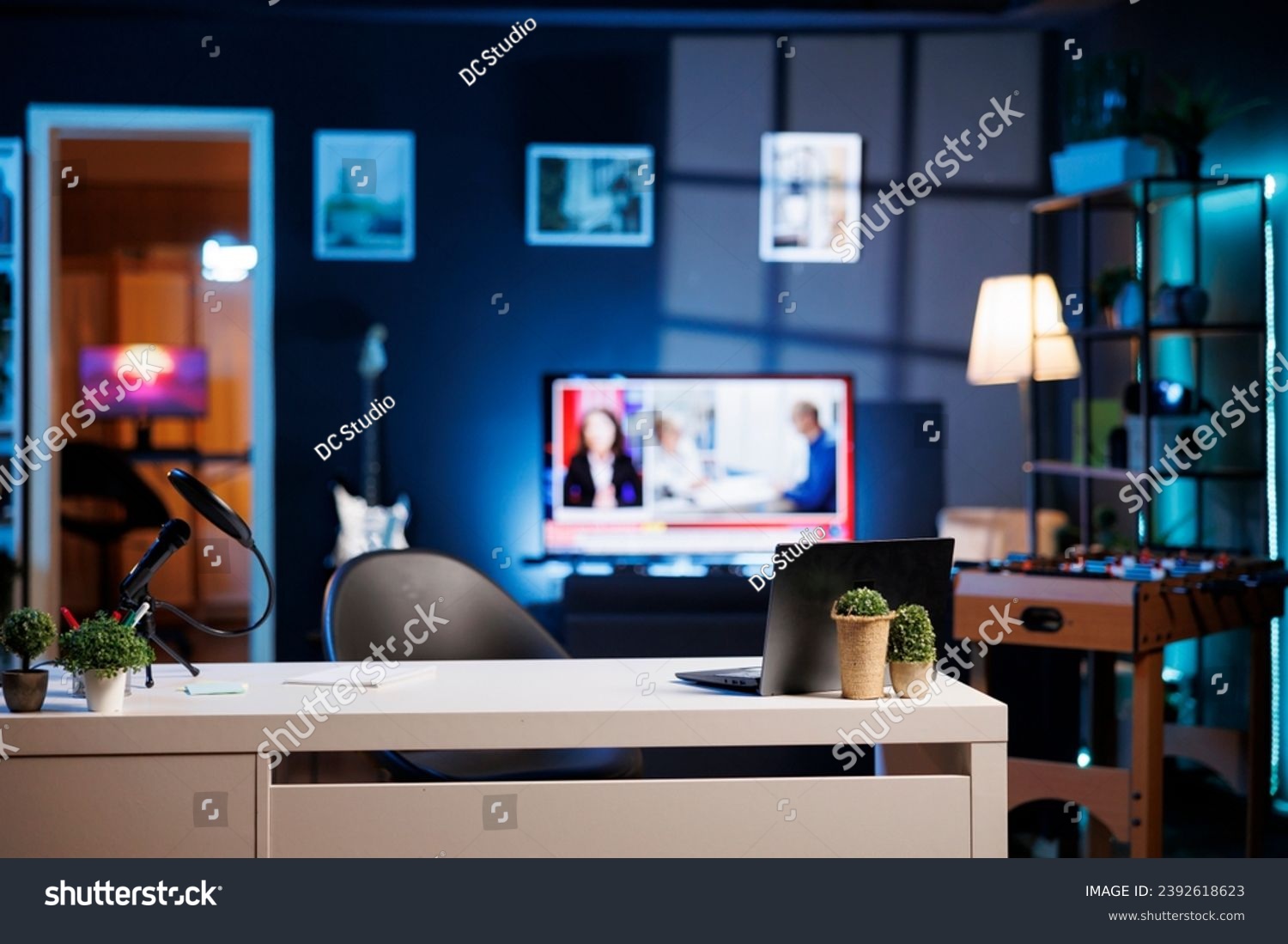 Empty home studio interior illuminated with neon lights at night, used for internet video production. Apartment filled with content creation equipment, TV running in blurry background #2392618623