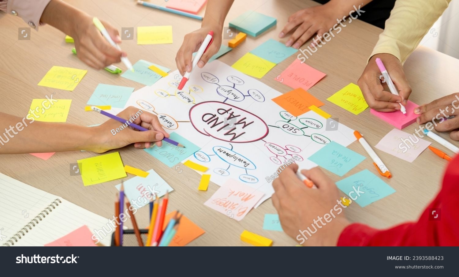 Professional startup group share creative marketing idea by using mind map. Young skilled business people brainstorm business plan while writing sticky notes. Focus on hand. Closeup. Variegated. #2393588423