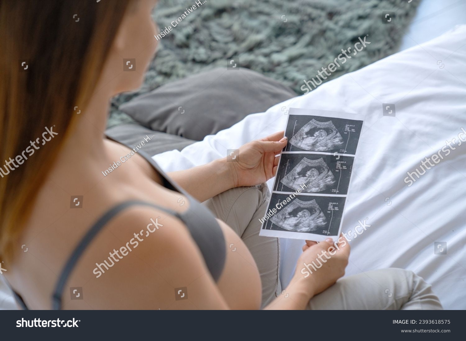 Pregnant woman looking at ultrasound scan of baby, close up of scan. X-ray image photo of fetus embryo. Expectant mother checking on medical document #2393618575