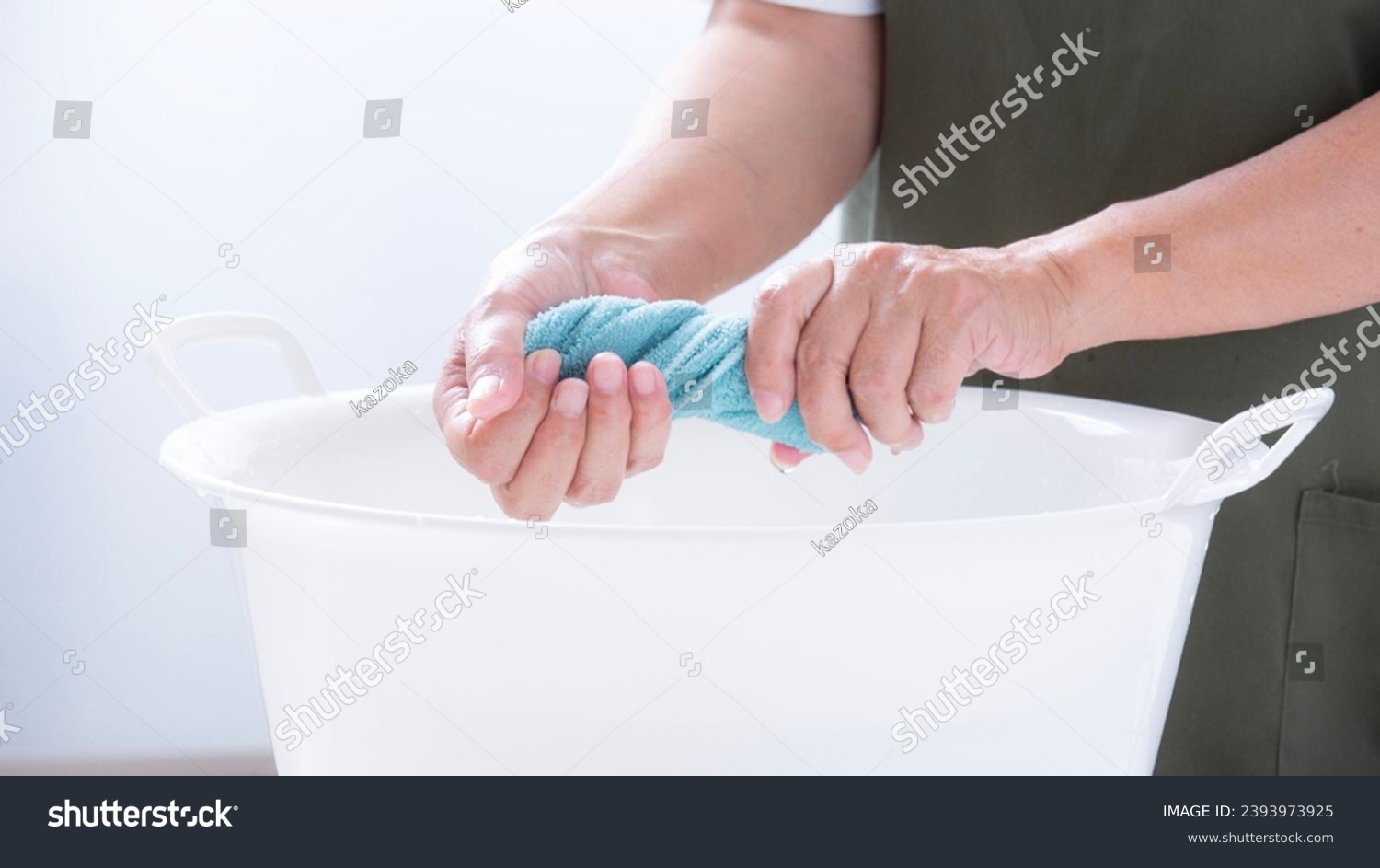 A woman's hand wringing a rag for cleaning,
Hands of a woman squeezing laundry
 #2393973925