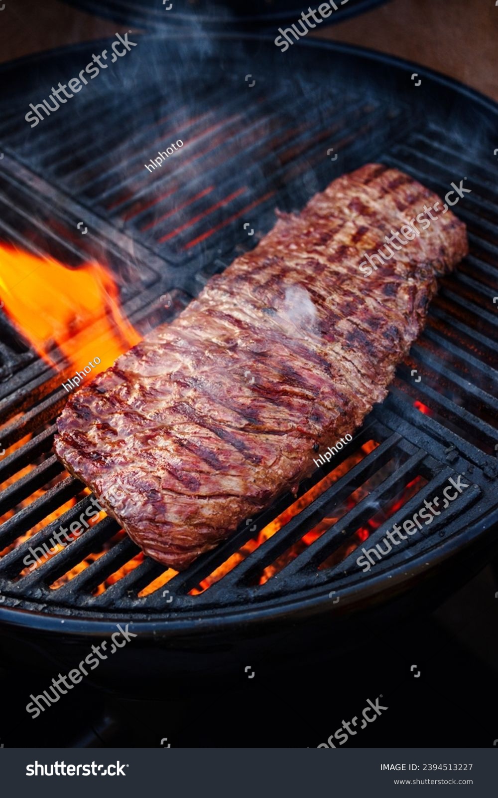 Traditional American barbecue bavette steak as close-up on a charcoal grill with fire  #2394513227