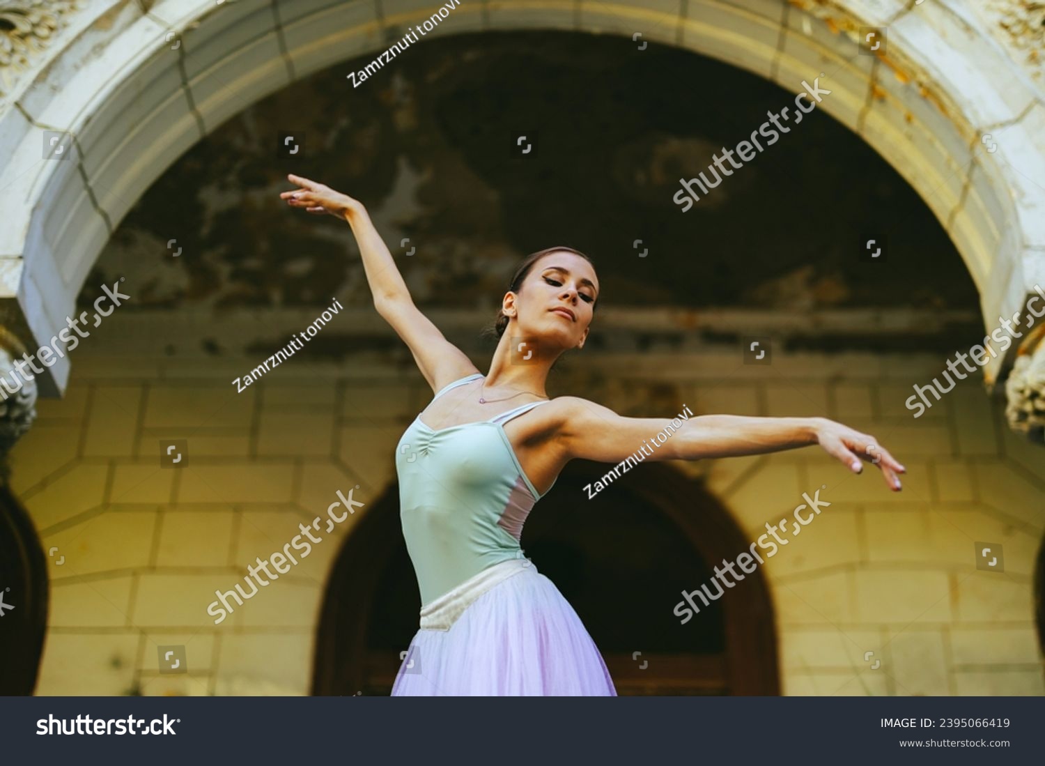 Portrait of a graceful classic ballerina woman with hair tied in a bun dancing while wearing white dress and enjoying in every movement. Grace and motion concept. Copy space. #2395066419