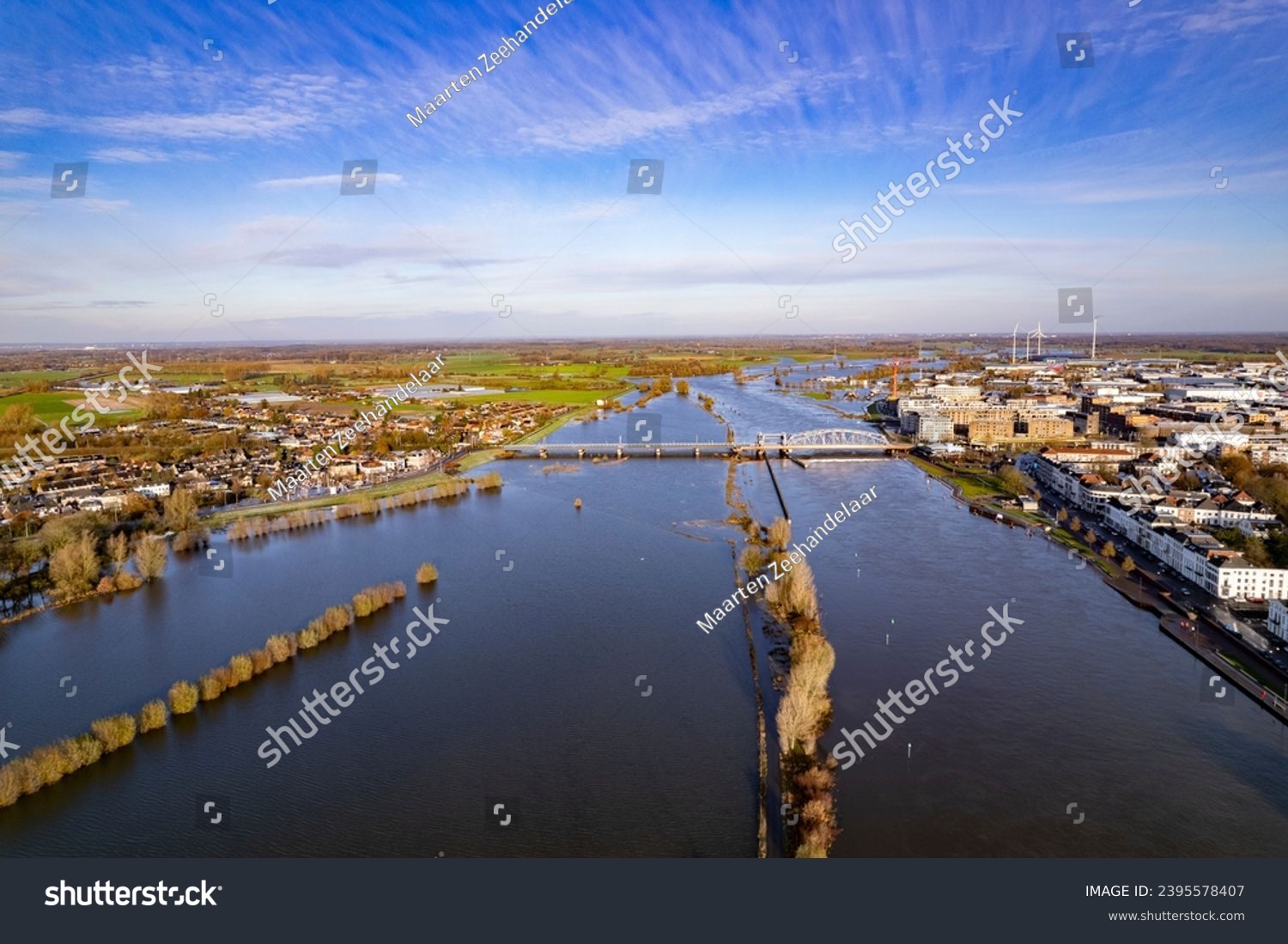 River IJssel being twice its size during high water levels in winter rains seen from above passing countenance boulevard of Zutphen, The Netherlands. Aerial of flooded floodplains at city limits. #2395578407