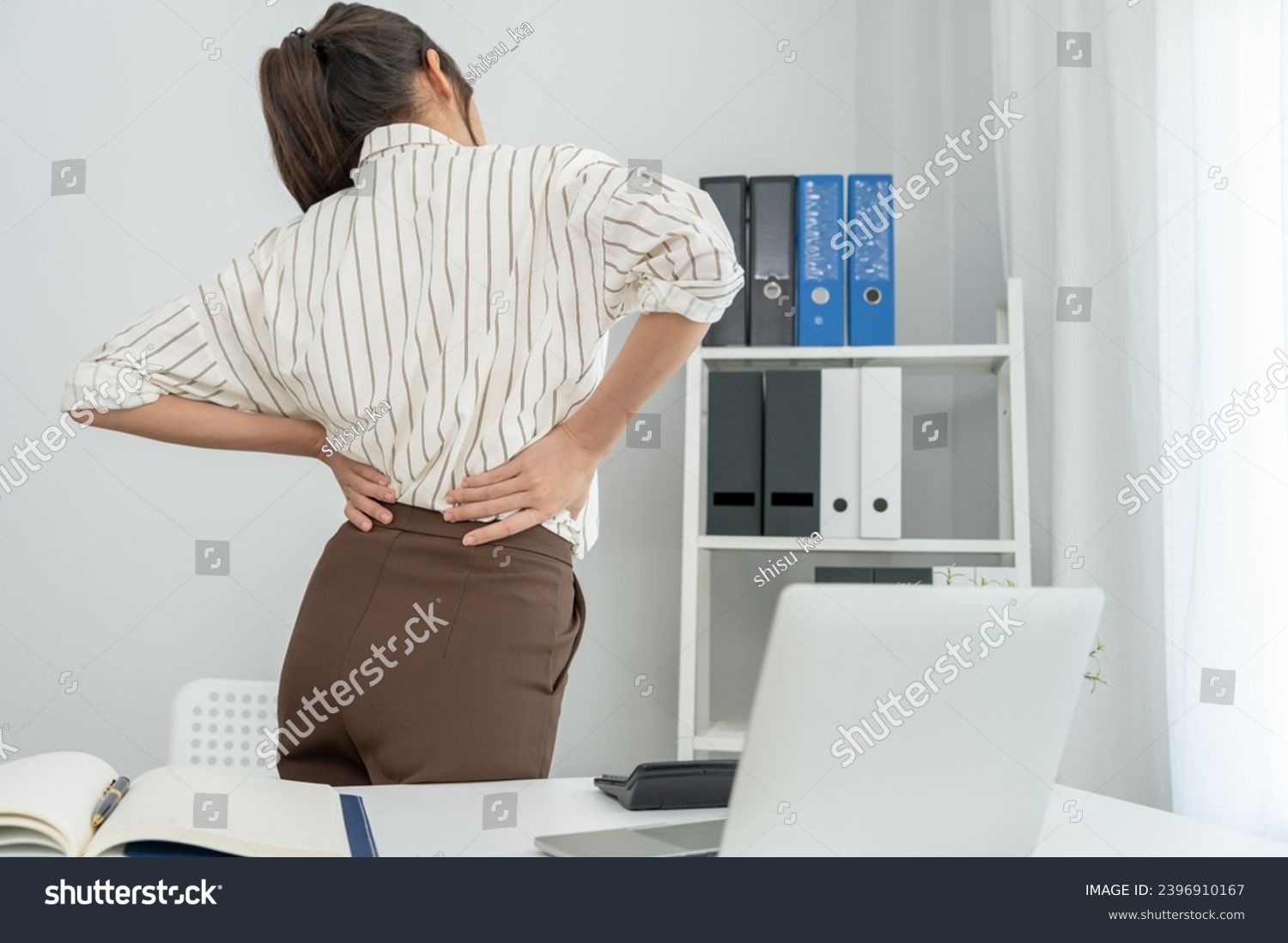 woman holding her lower back while and suffer from unbearable pain health and problems, chronic back pain, backache in office syndrome, scoliosis, herniated disc, muscle inflammation #2396910167