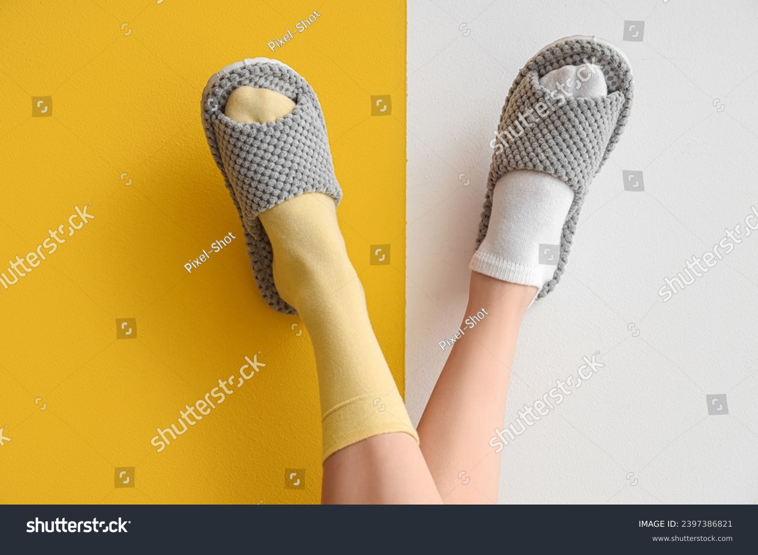 Female legs in soft slippers on yellow and white background #2397386821