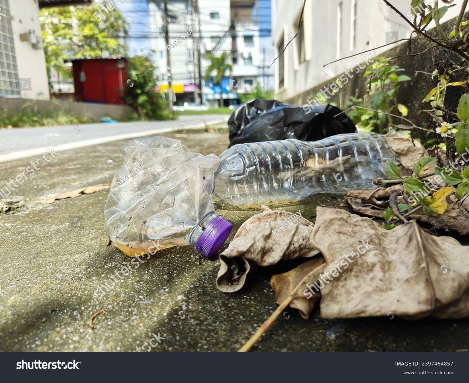 Garbage on the sidewalk, including water bottles and plastic bags, is dirty and blocks the walkway.  It's caused by people not throwing it into the bin. #2397464857