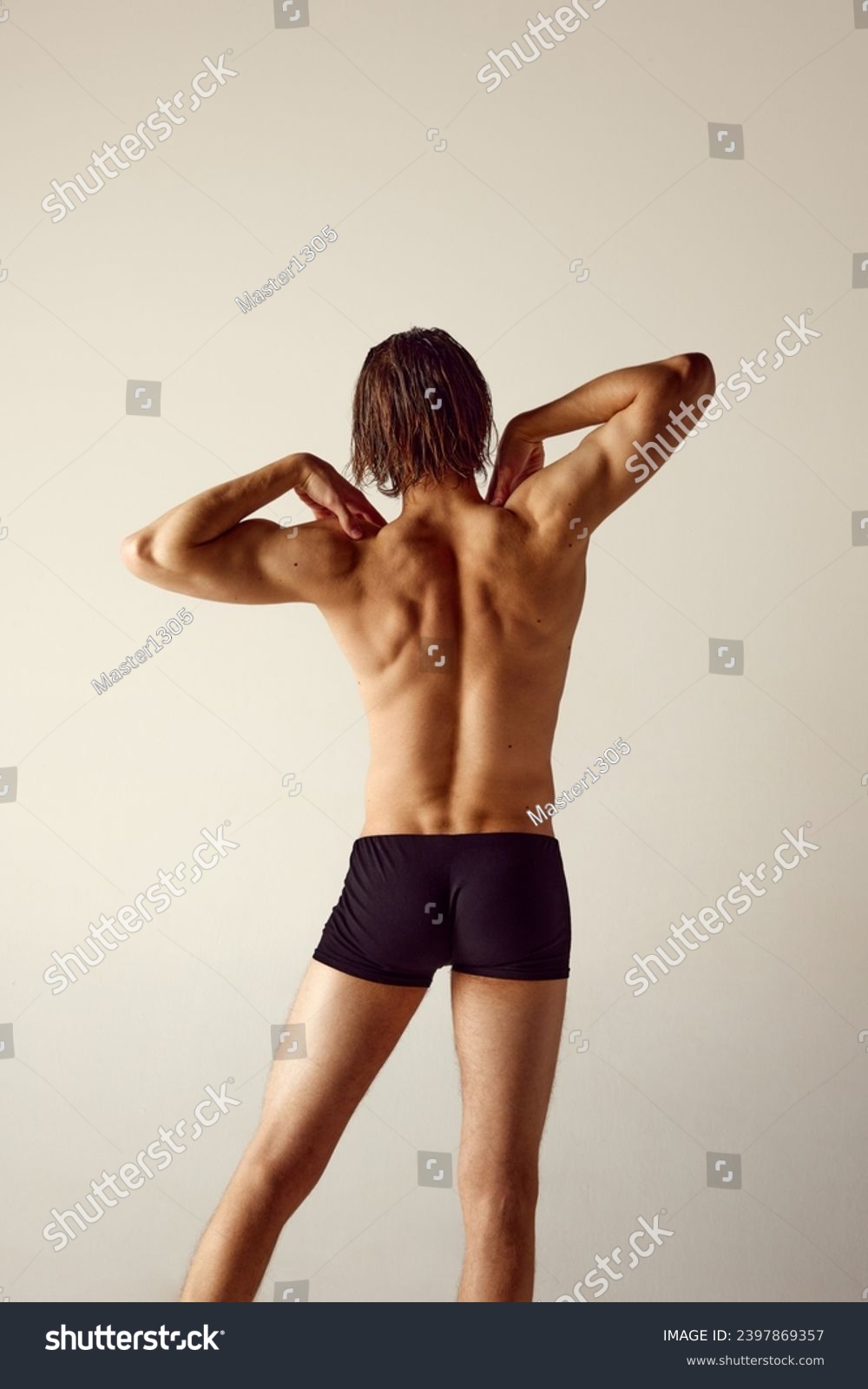 Shirtless young man with fit body standing in underwear against grey studio background. Relief strong healthy back, spine. Concept of men's beauty, health, body care, sportive lifestyle #2397869357