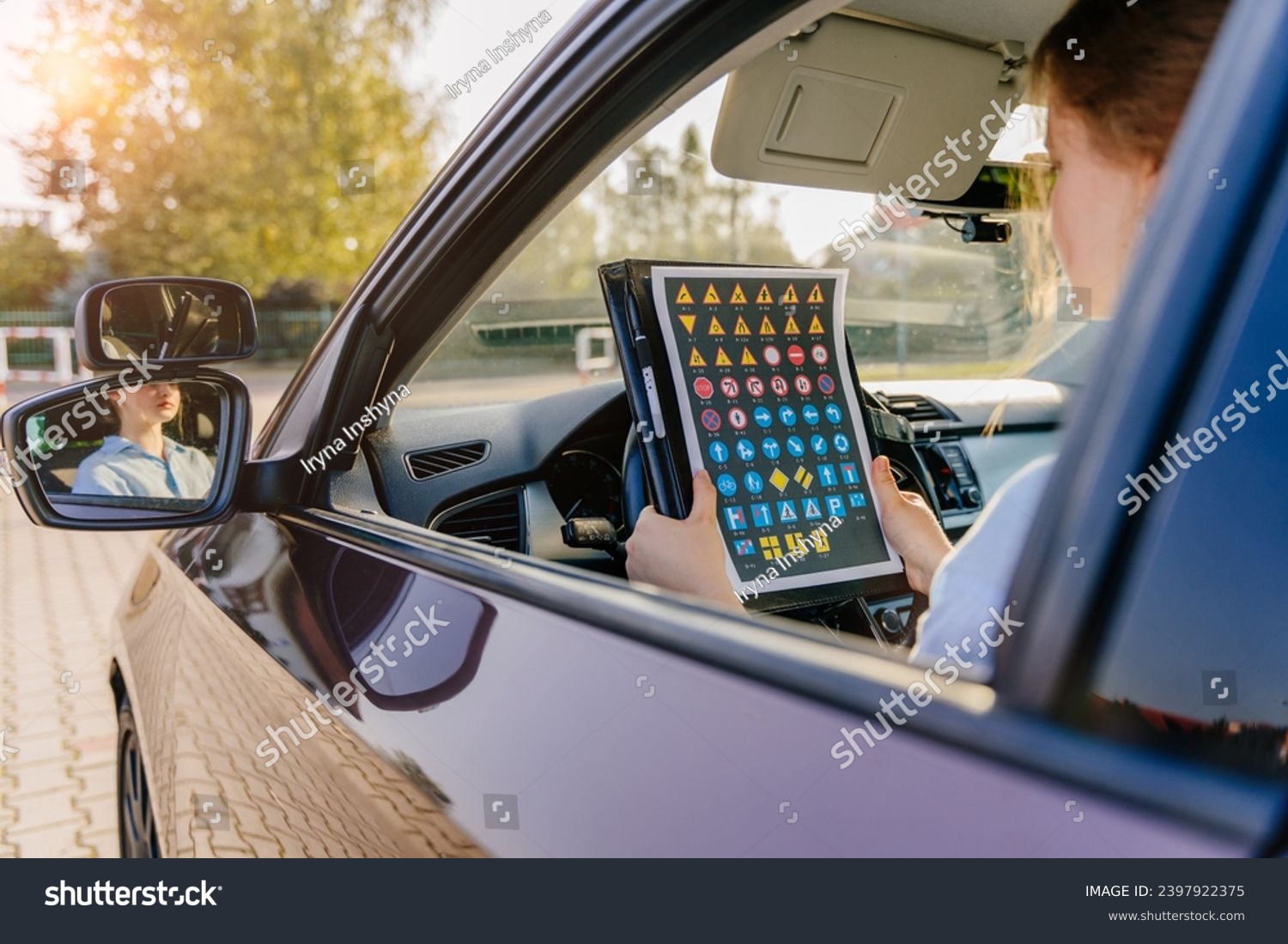 Young girl learns road signs while sitting in a car passing the driving test. Driving school novice driver concept. #2397922375