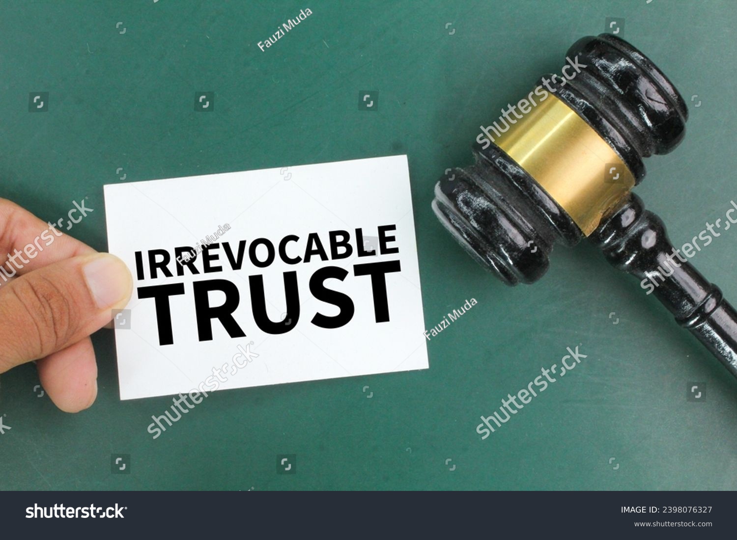 judge's gavel and hand holding colored paper with the word Irrevocable trust. the concept of trust #2398076327